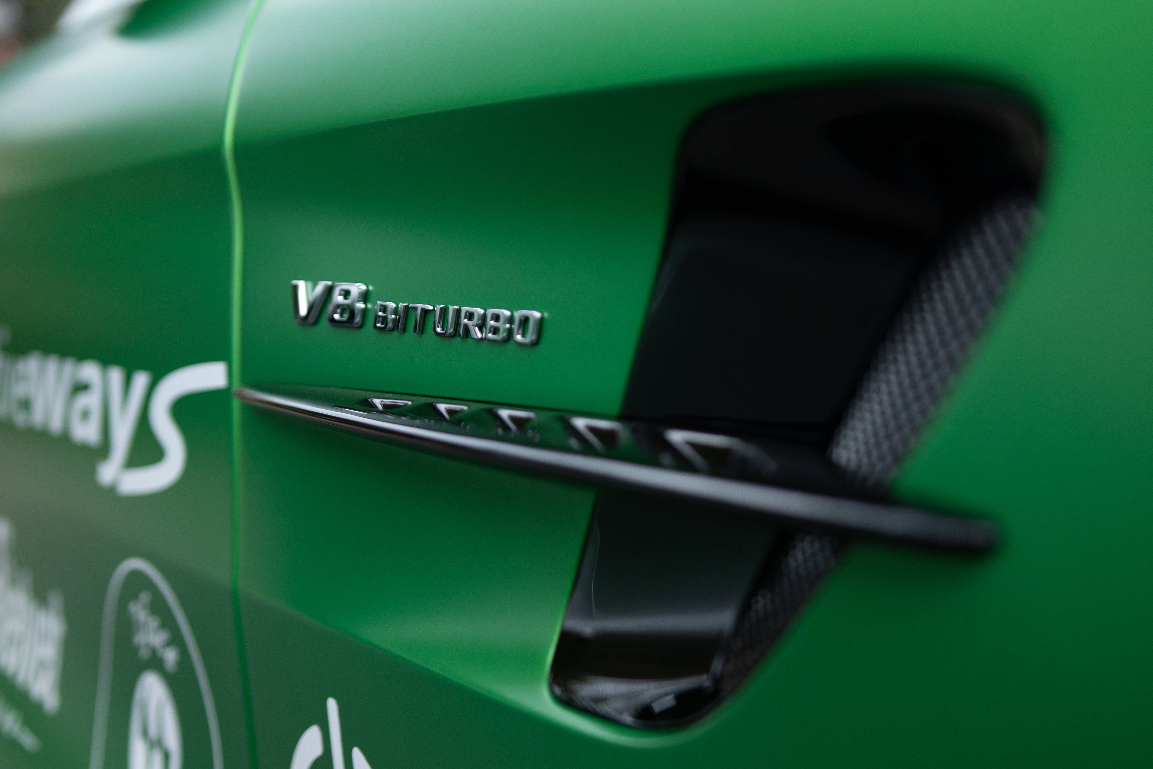 AMG iPhone 桌布 壁紙 — 鮮綠色跑車車門特寫，展示 'V8 BITURBO' 徽章和碳纖維通風口。