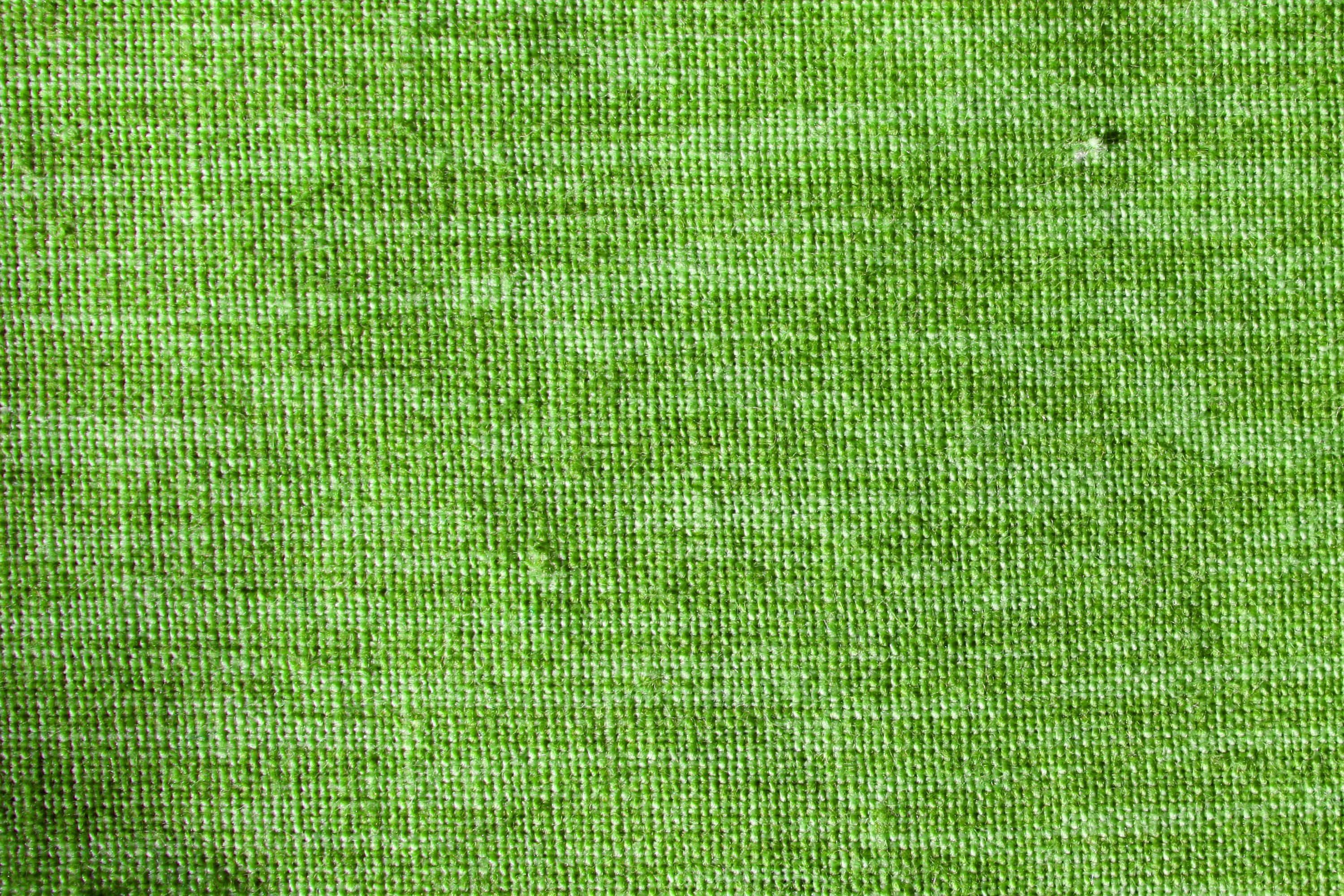 Green Texture 桌布 壁紙 — 鮮綠色針織布料的特寫，帶有細微紋理，右上角附近有一個微小的暗點。