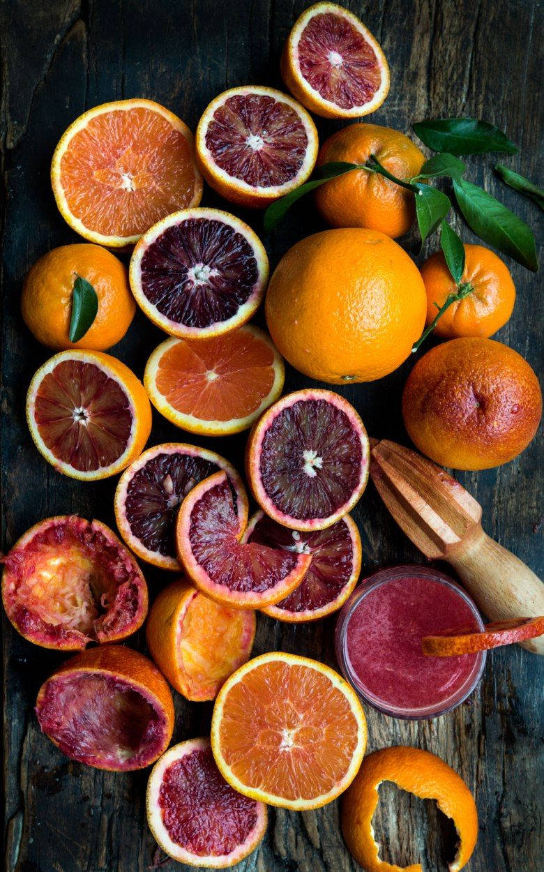 Fruit 桌布 壁紙 — 鮮血橙切片，露出深紅色的果肉，散落在深色鄉村風木頭上，搭配新鮮果汁和柑橘工具。