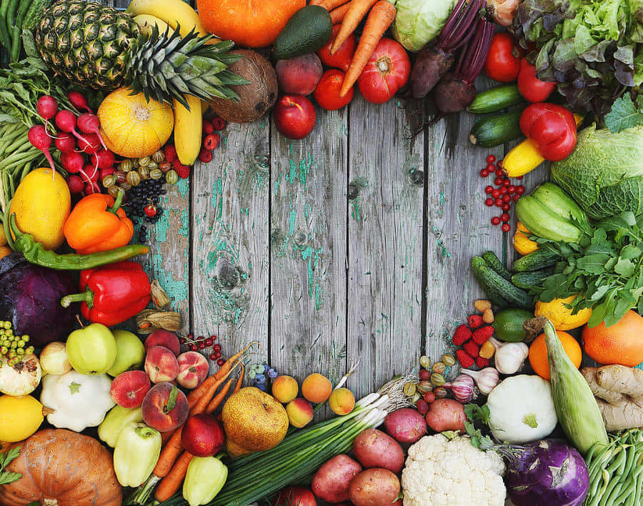 Fruits And Vegetables 桌布 壁紙 — 鮮豔多樣的新鮮水果和蔬菜排列在一個圓形框架內，圍繞著一塊風化的木質表面。