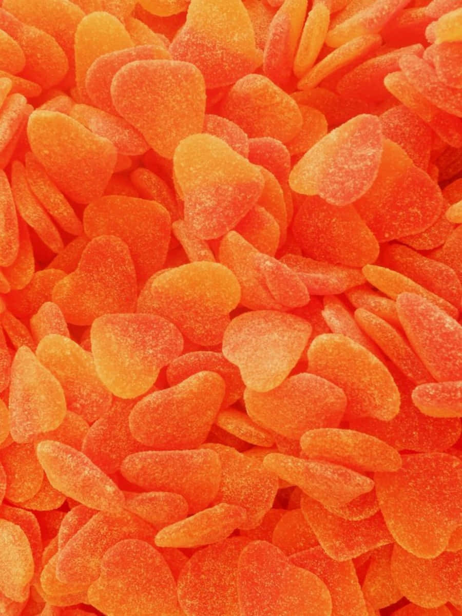 Orange Heart 桌布 壁紙 — 鮮豔橙色軟糖的微距特寫，表面覆蓋糖晶體，密集堆疊，帶有光澤。