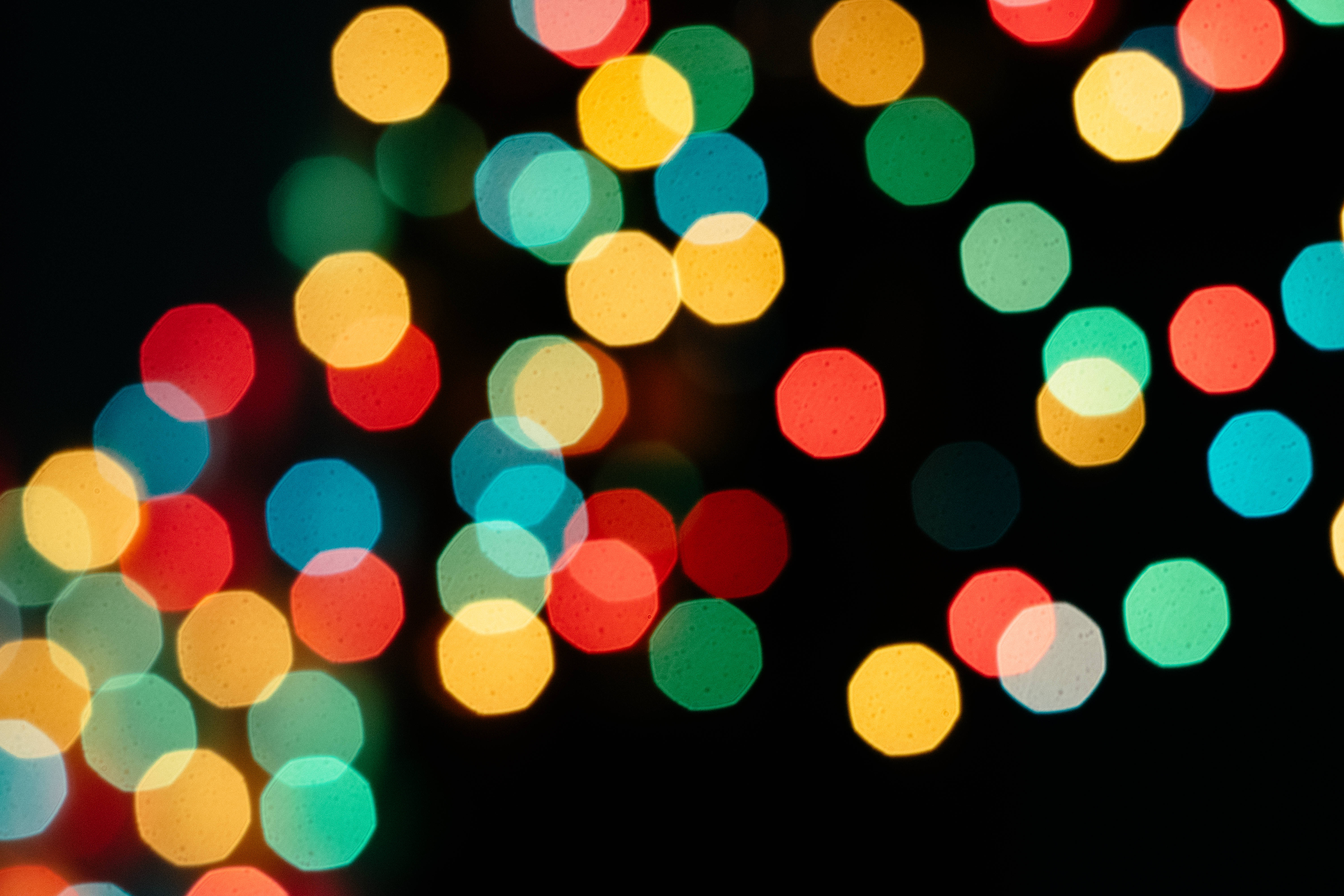 Bokeh 桌布 壁紙 — 鮮豔的圓形散景燈光，紅色、黃色、綠色和藍色，在深黑色背景上柔和發光。