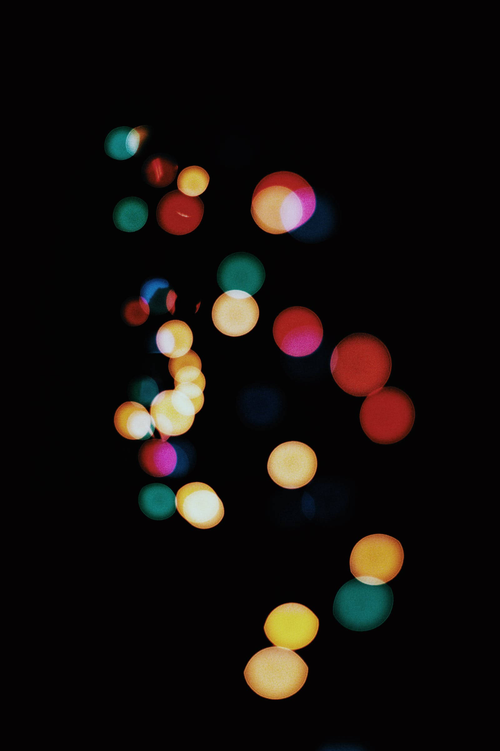 Bokeh 桌布 壁紙 — 鮮豔的圓形散景燈光（紅色、黃色、綠色和粉紅色）漂浮在深黑色背景上。