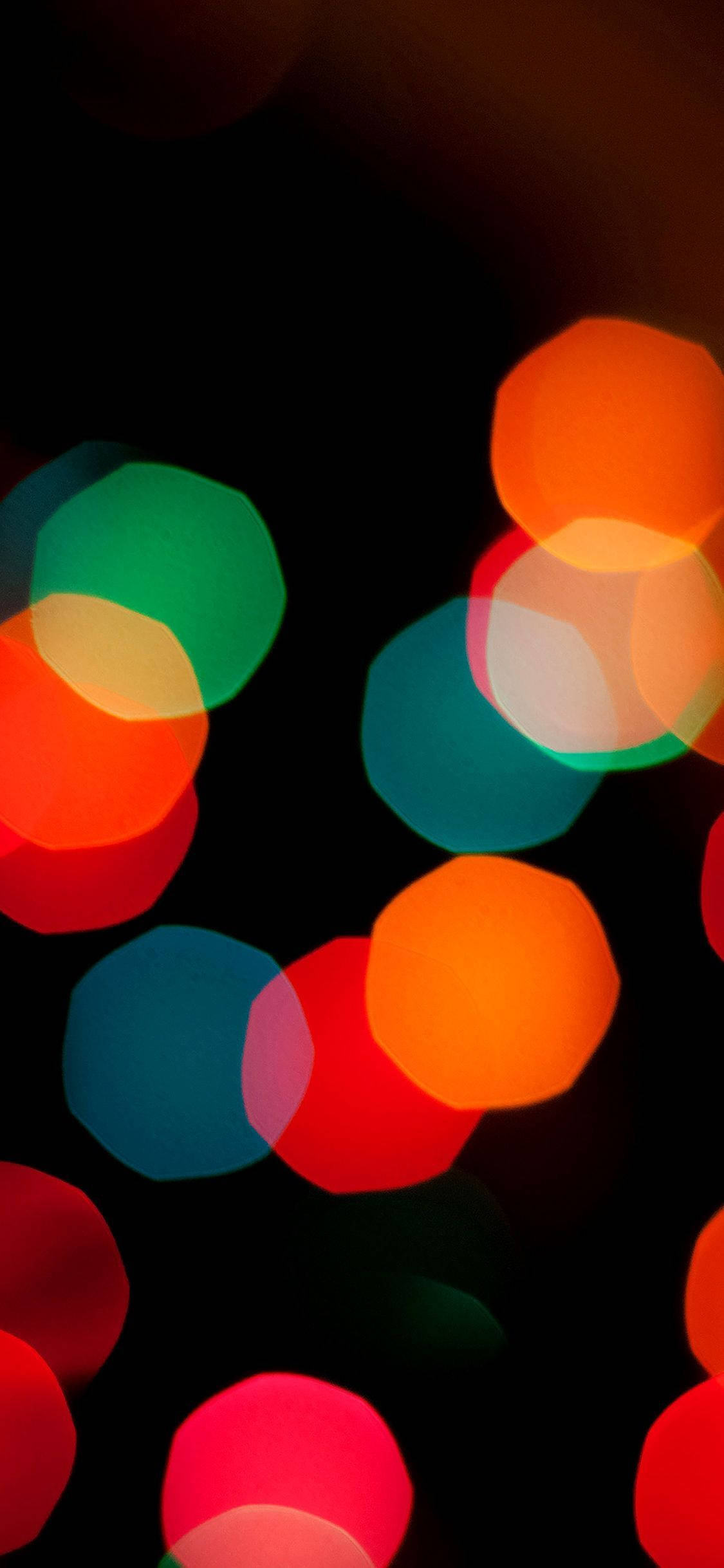 iOS 桌布 壁紙 — 鮮豔的圓形散景燈光以紅色、綠色和藍色柔和地發光，映襯在深黑色背景上。