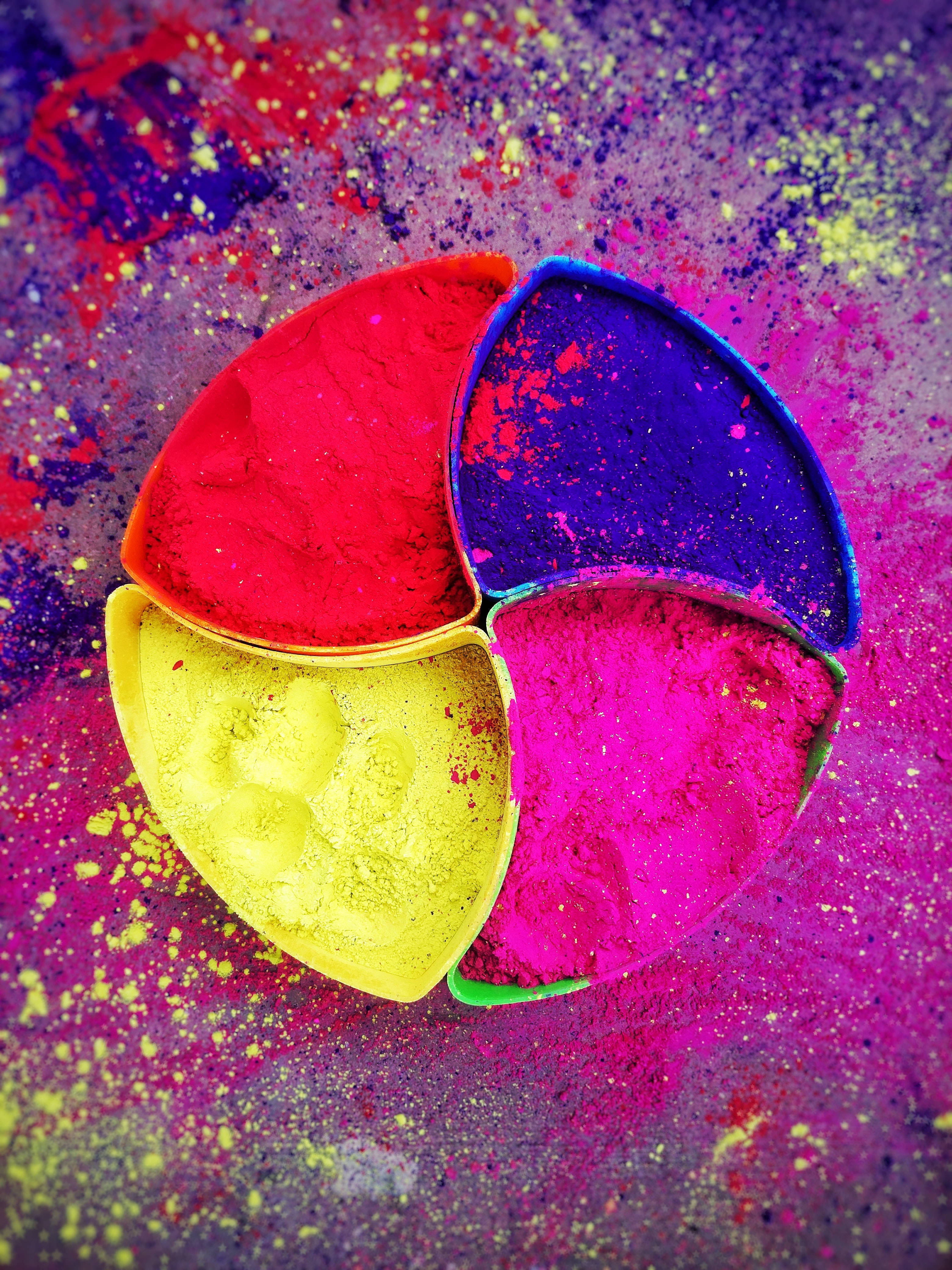 Holi 桌布 壁紙 — 鮮豔的彩色粉末在分格托盤中，濺灑在生動的紫色背景上。