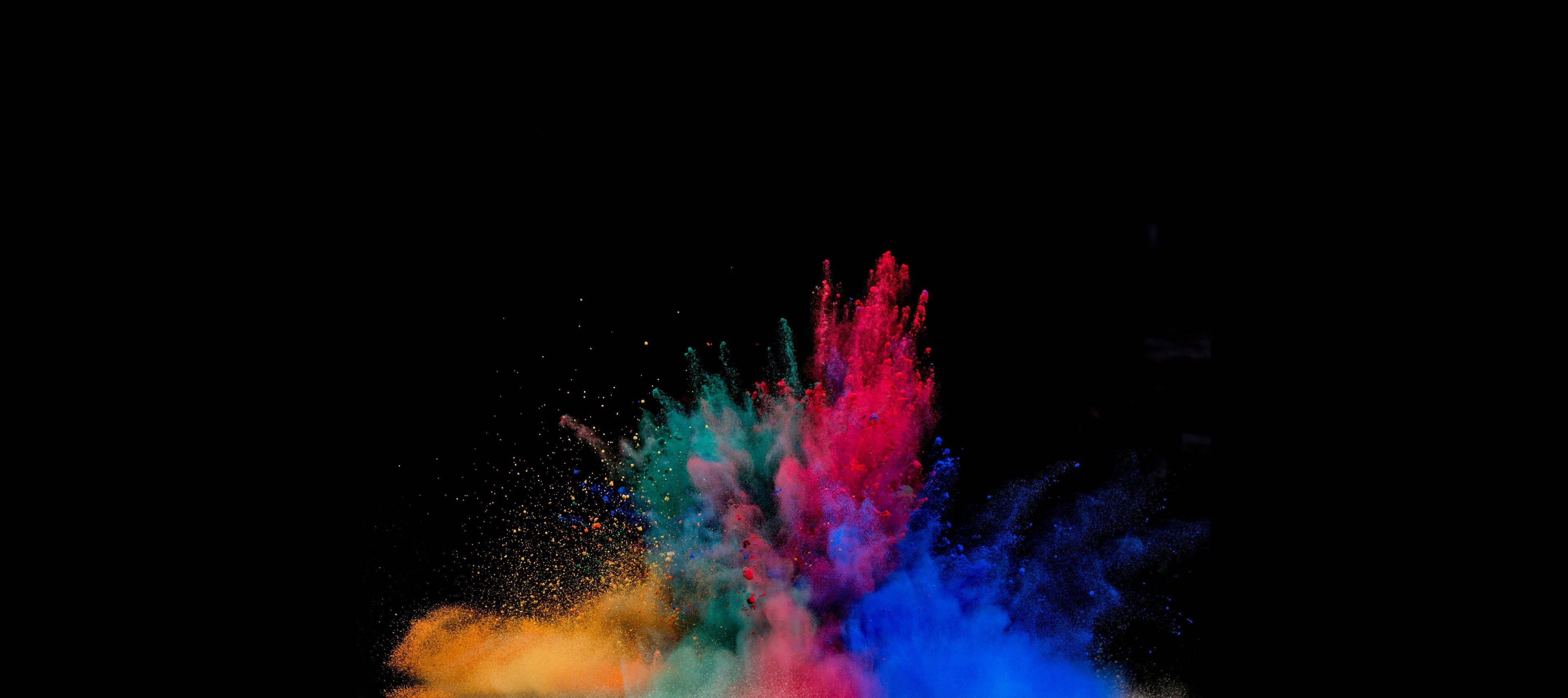 AMOLED 4K 桌布 壁紙 — 鮮豔的彩色粉末在純黑色背景上動態爆炸，產生紅色、藍色、綠色和橙色的驚人爆發。