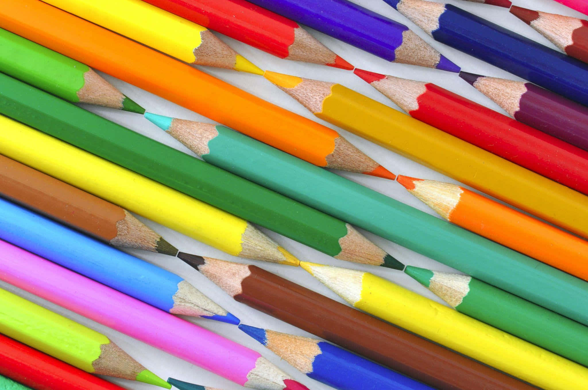 crayon 桌布 壁紙 — 鮮豔的彩色鉛筆以對角線排列在白色背景上，展示尖銳的筆尖和木紋質感。
