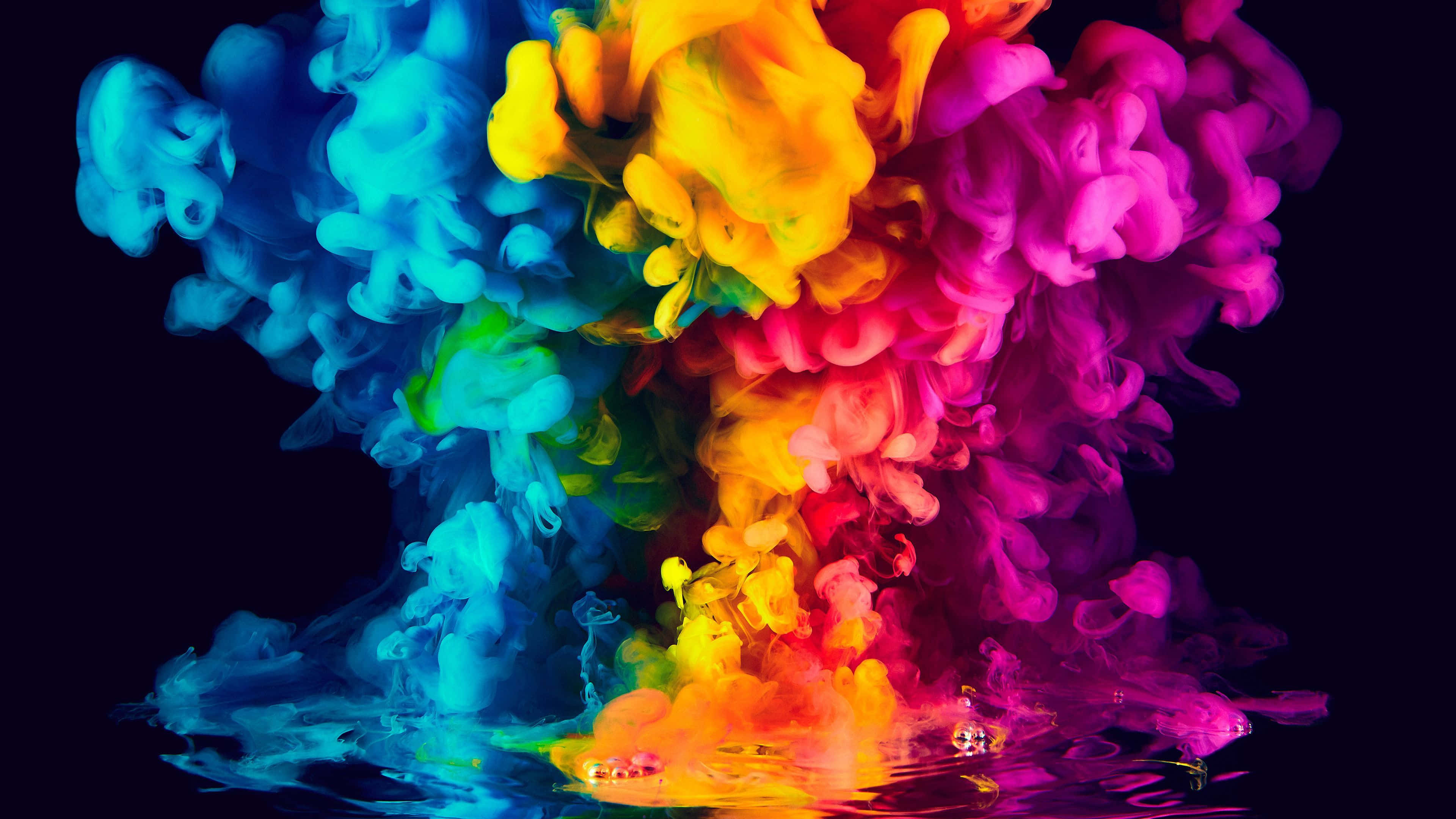 Color Smoke 桌布 壁紙 — 鮮豔的彩虹墨水漩渦在黑色背景的水中爆炸，創造出動感多彩的抽象場景。