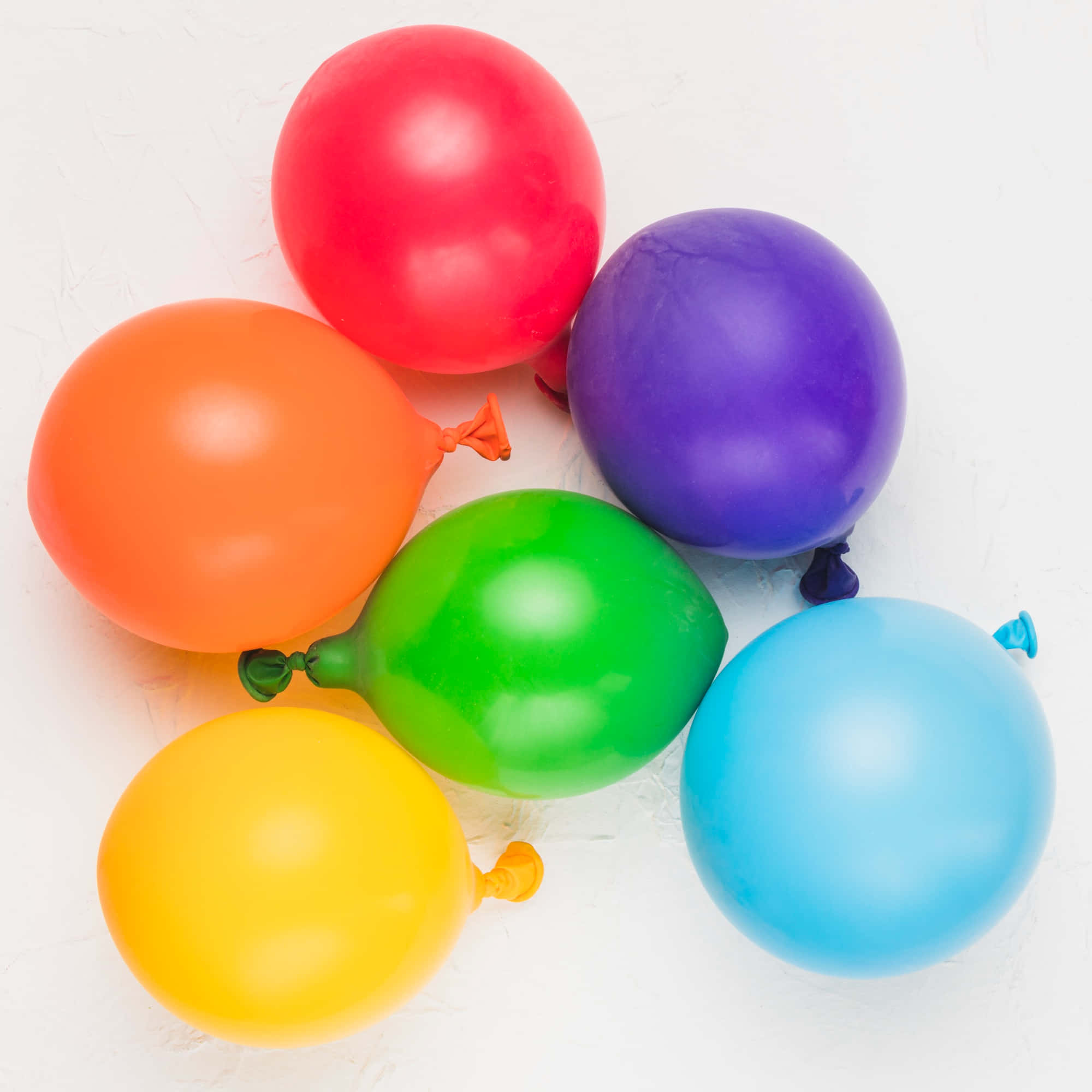 Balloon 桌布 壁紙 — 鮮豔的彩虹氣球，有紅色、橙色、綠色、藍色、紫色和黃色，漂浮在帶有紋理的白色背景上。