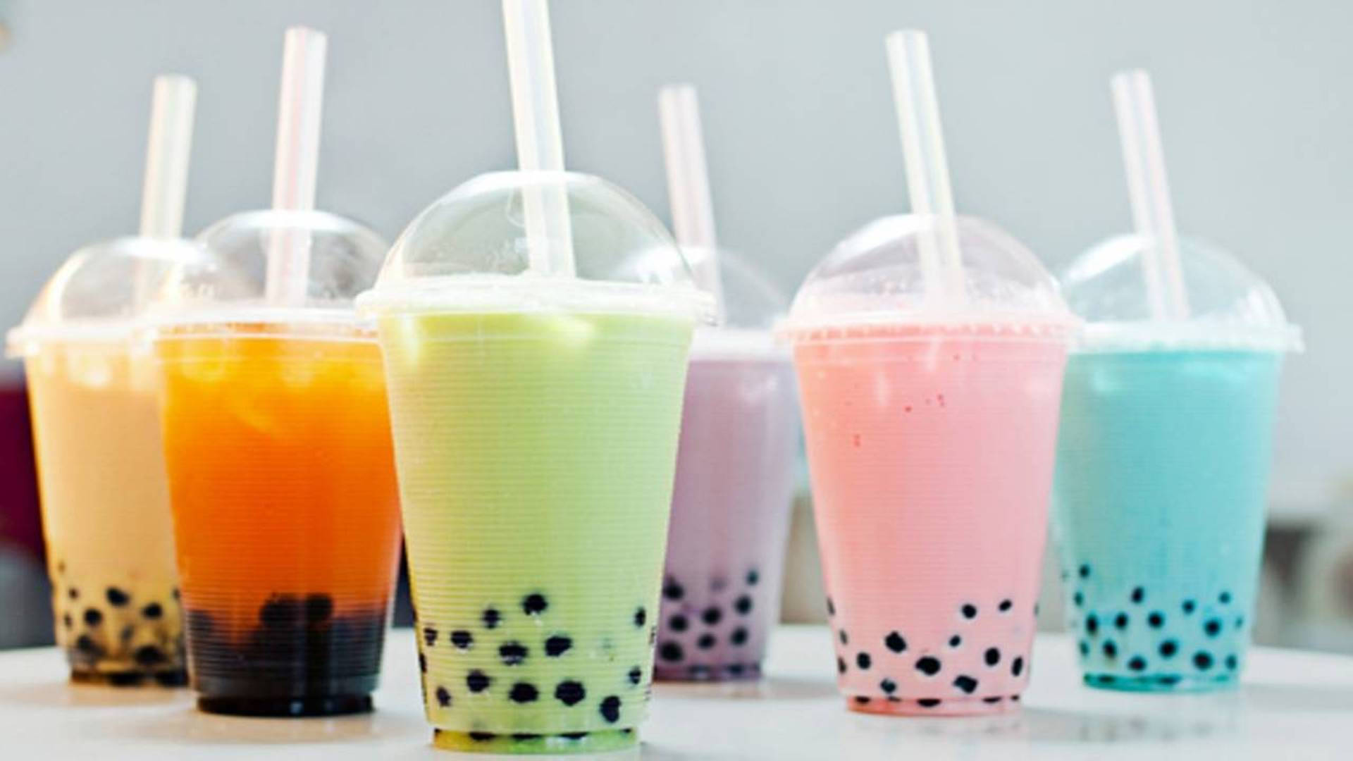 Bubble 桌布 壁紙 — 鮮豔的彩虹珍珠奶茶飲品，放在透明杯中，插上吸管，排列在白色表面上。