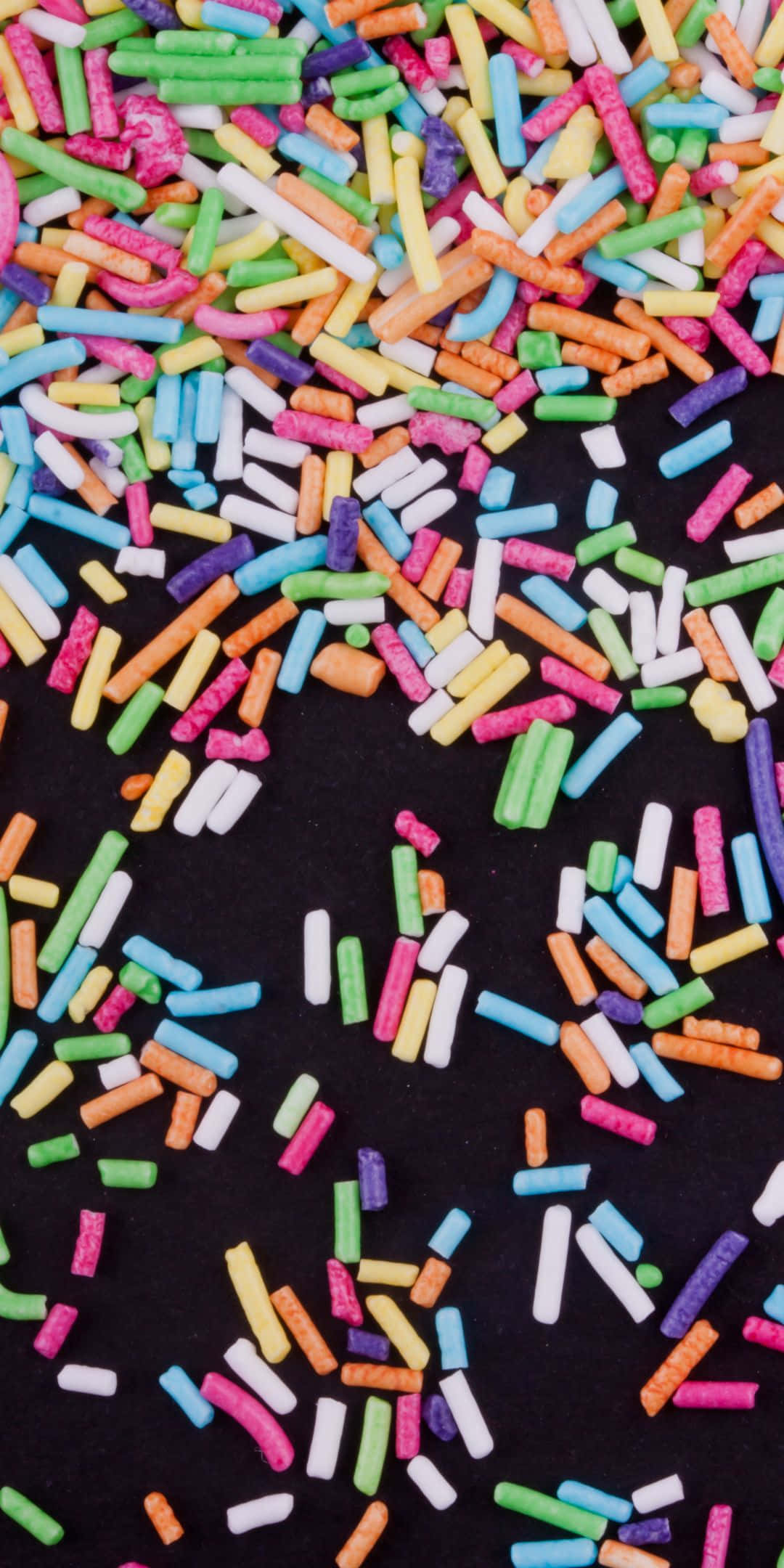 Sprinkles 桌布 壁紙 — 鮮豔的彩虹糖針密集地散落在純黑背景上，營造出俏皮甜點的質感。