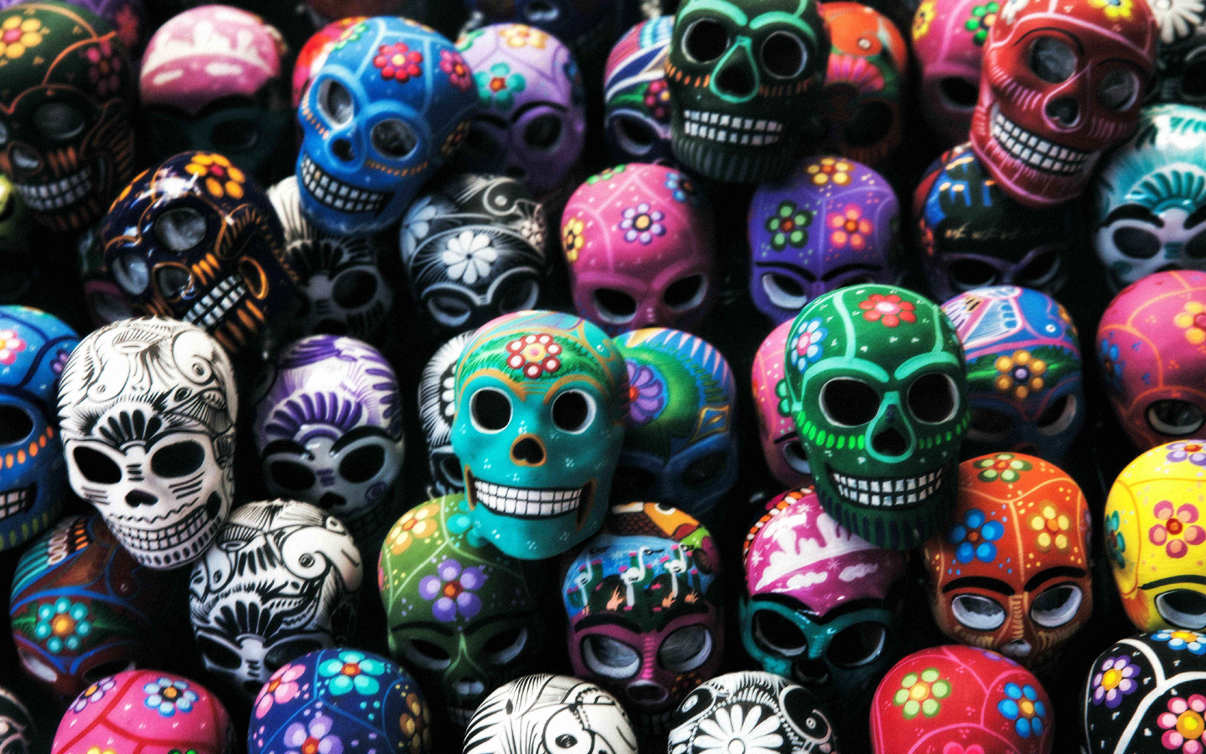 Dia De Los Muertos 桌布 壁紙 — 鮮豔的手繪糖骷髏，以大膽色彩和花卉圖案緊密排列。