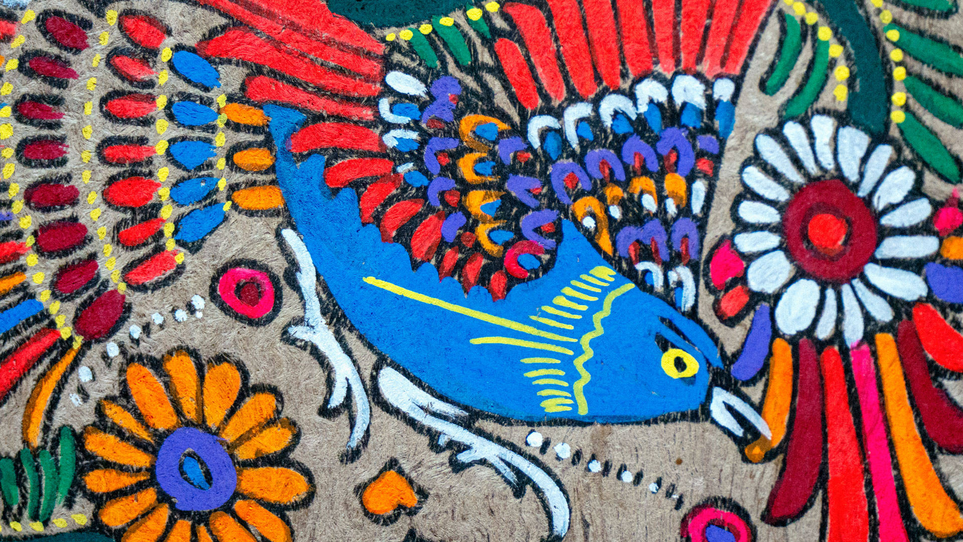 Folk Art 桌布 壁紙 — 鮮豔的手繪藍鳥，紅色尾巴和黃色眼睛，棲息在紋理布料上的彩色花朵之間。