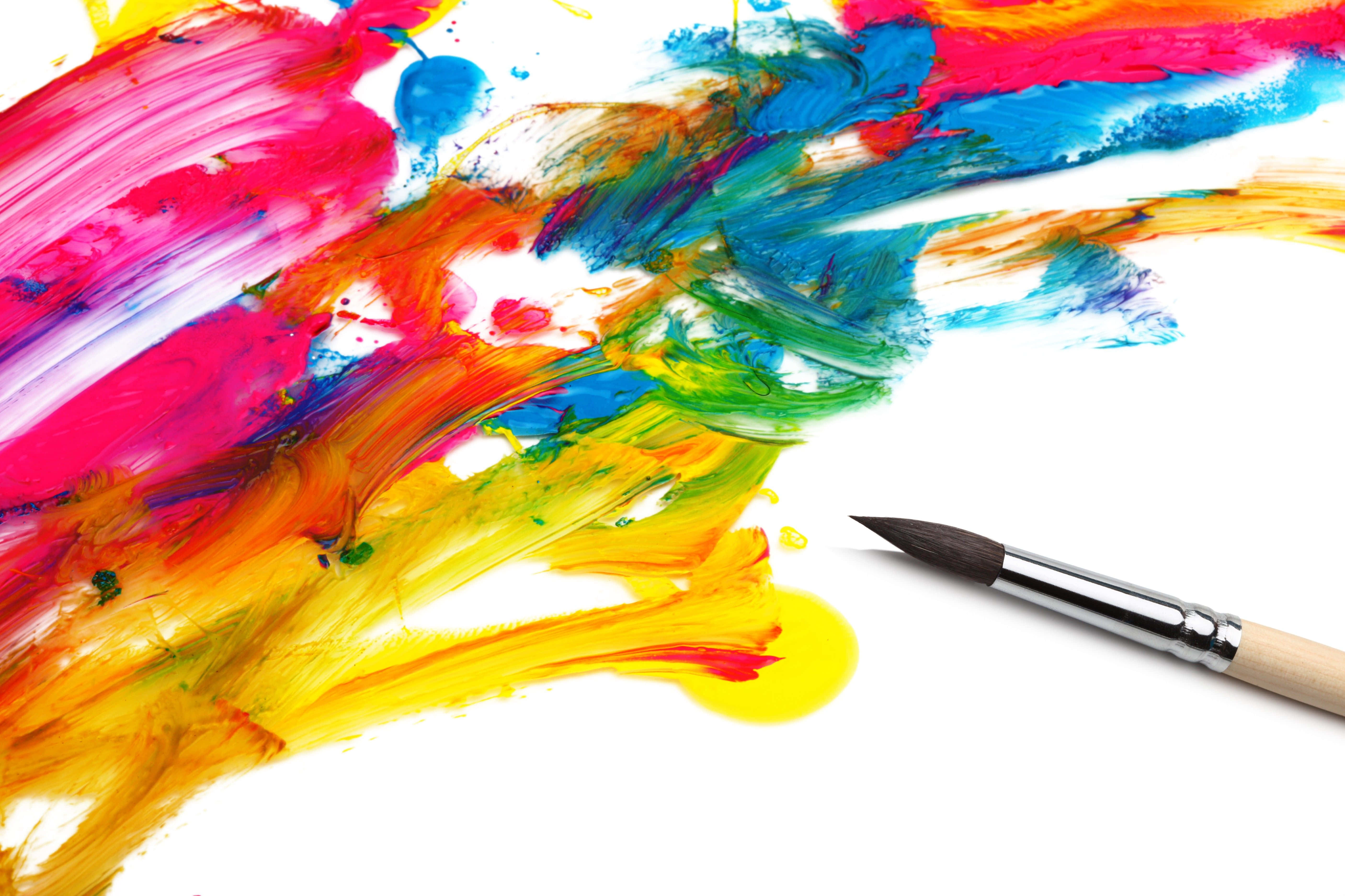 paint 桌布 壁紙 — 鮮豔的抽象顏料筆觸以大膽的色彩在白色畫布上爆發，旁邊放著一支畫筆。