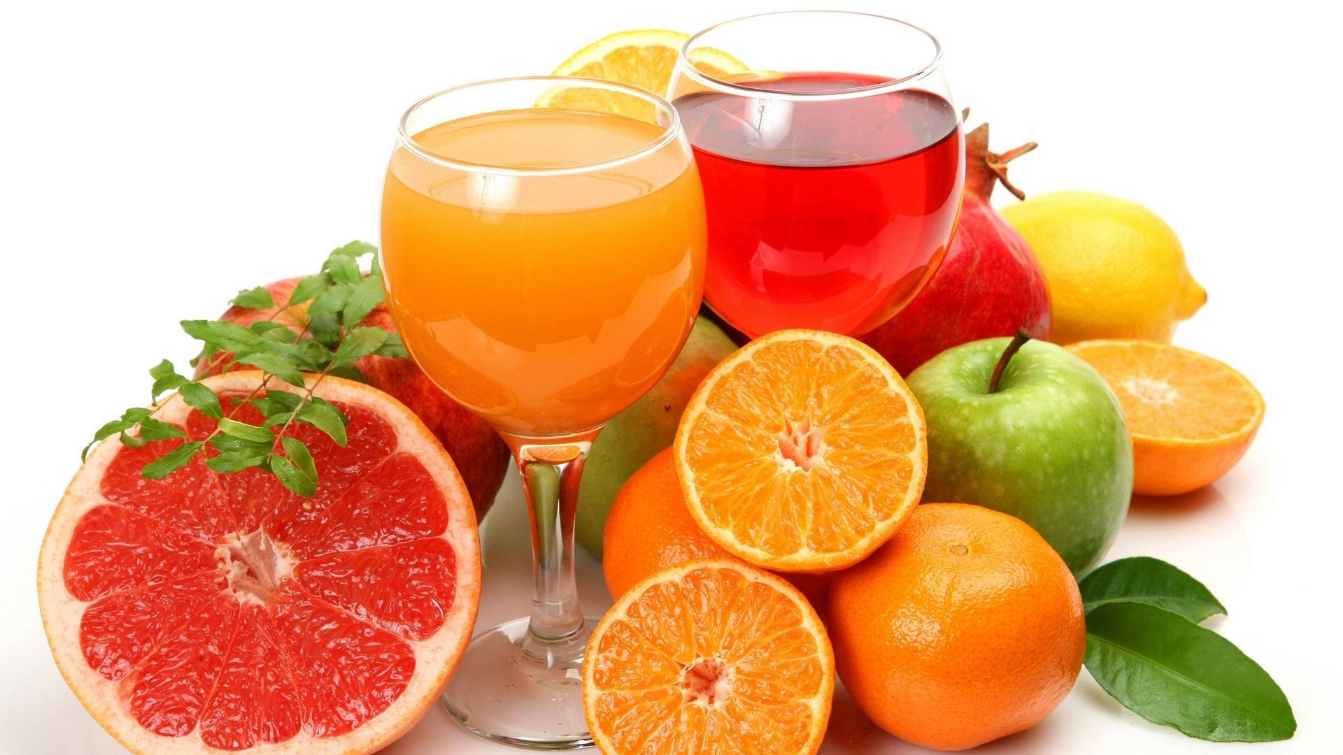 Fruits 桌布 壁紙 — 鮮豔的柑橘類水果和果汁杯排列在白色背景上，搭配新鮮綠葉。