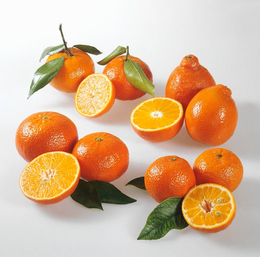 Fruits 桌布 壁紙 — 鮮豔的柳橙配綠葉和多汁的半塊，整齊排列在潔白的表面上。