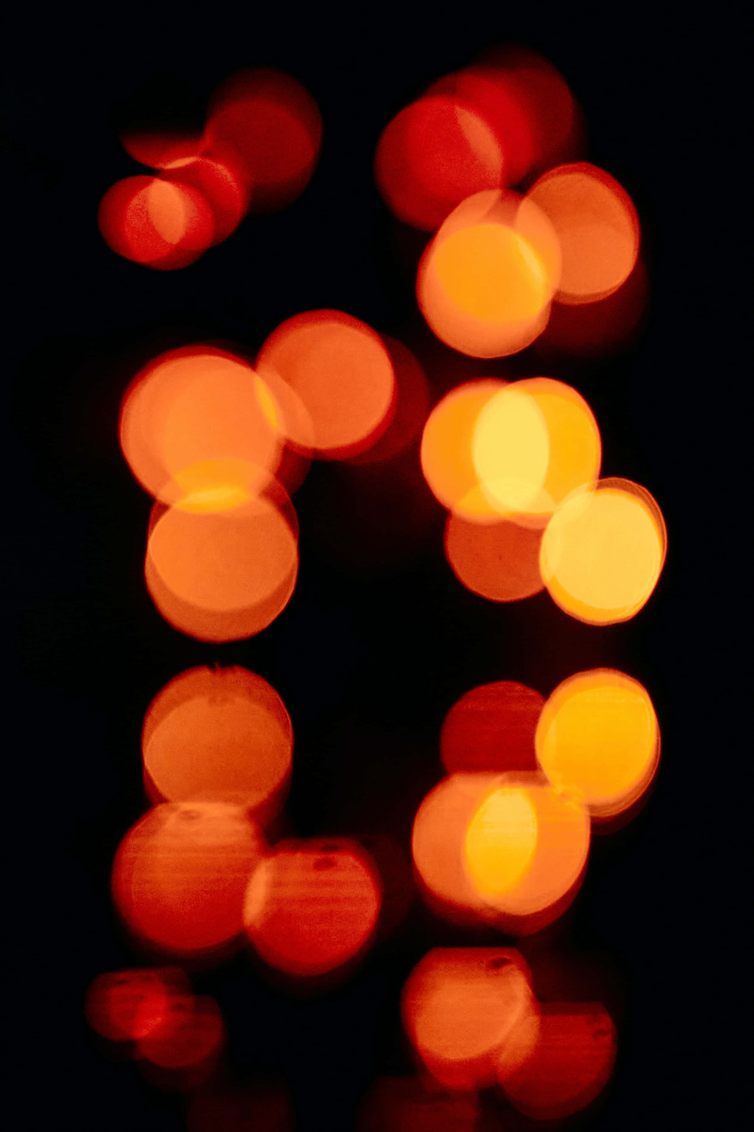 Bokeh 桌布 壁紙 — 鮮豔的橙色和紅色散景燈光在深黑色背景上柔和地發光，營造出夢幻般的抽象夜景。