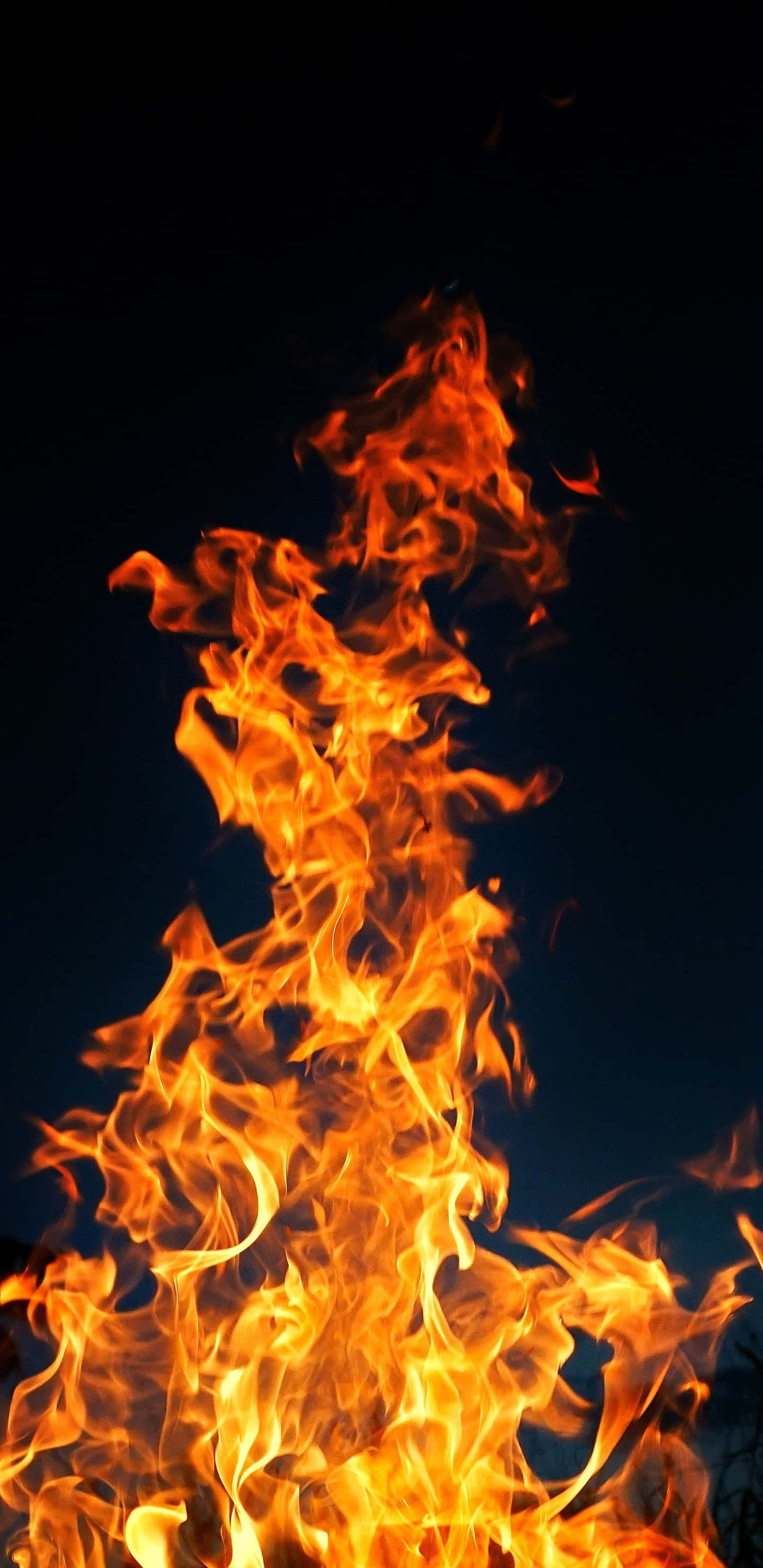 Android Fire 桌布 壁紙 — 鮮豔的橙色和黃色火焰在深邃的黑色夜空下向上翻騰，營造出戲劇性且強烈的視覺效果。