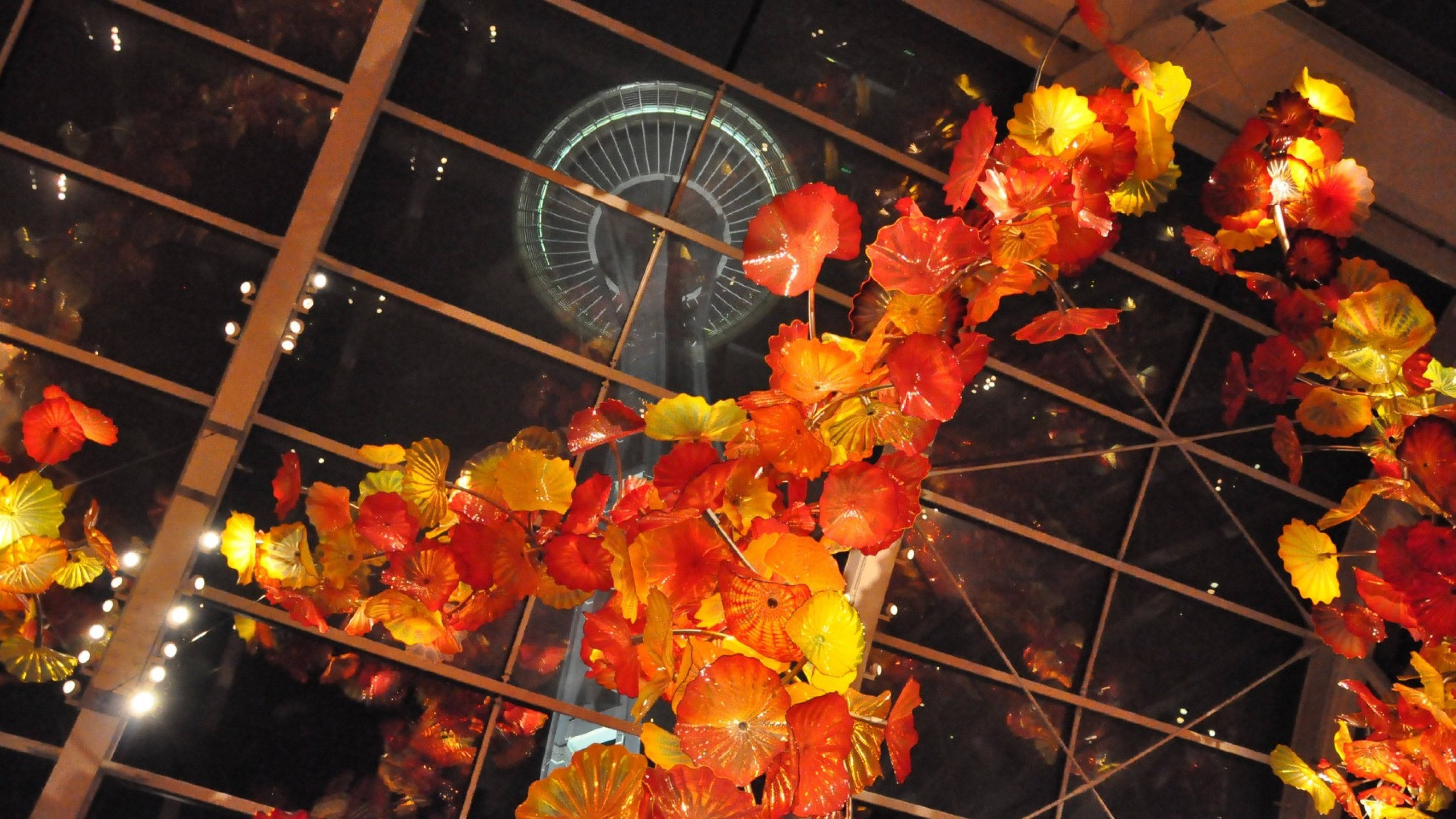 Space Needle 桌布 壁紙 — 鮮豔的橙色和黃色玻璃葉從玻璃天花板上垂下，透過夜空可見西雅圖太空針塔。