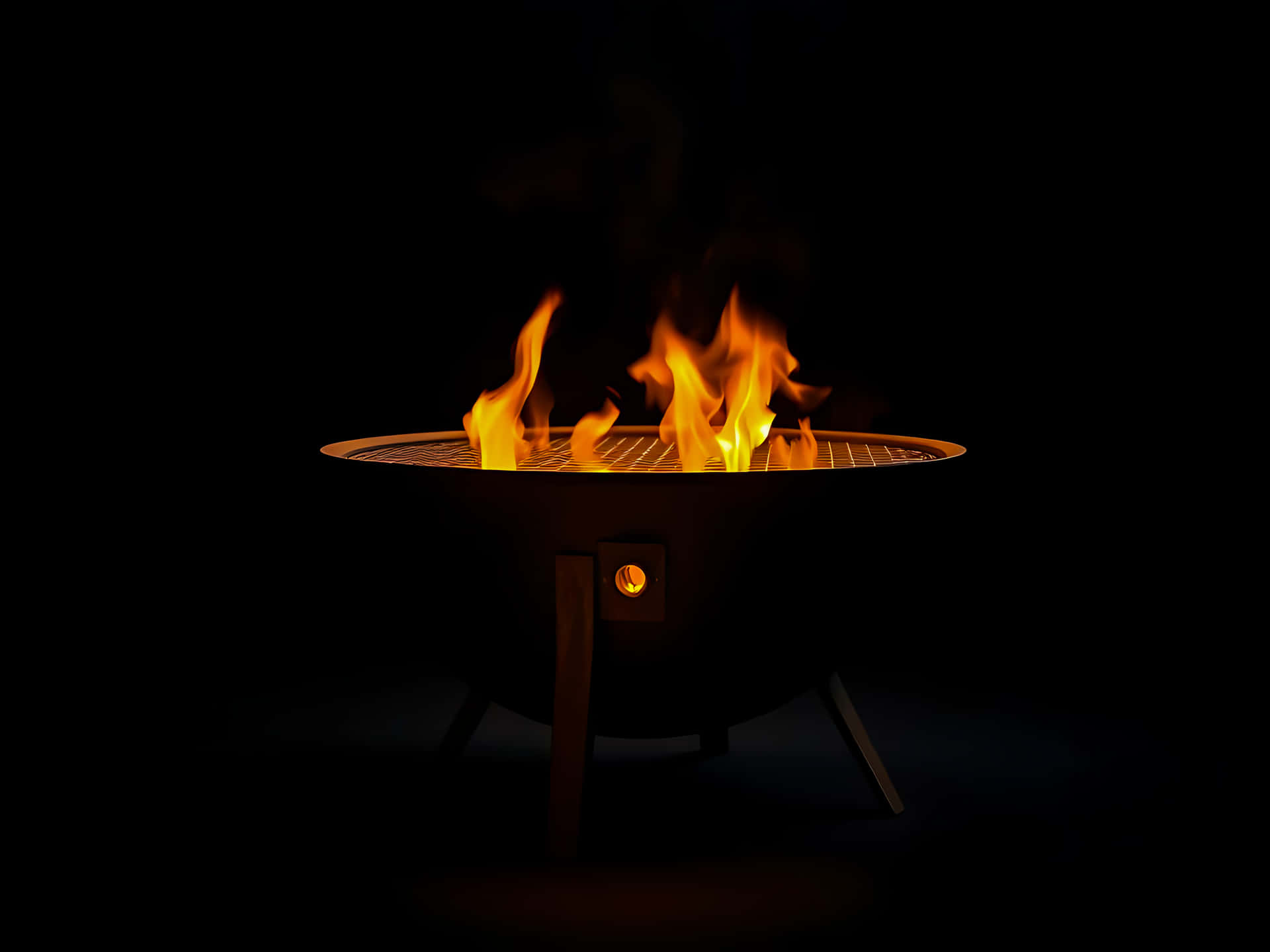 Modern fire pit with bright flames isolated on black background 壁紙 — 鮮豔的橙色火焰在圓形金屬火坑上舞動，背景為漆黑一片。