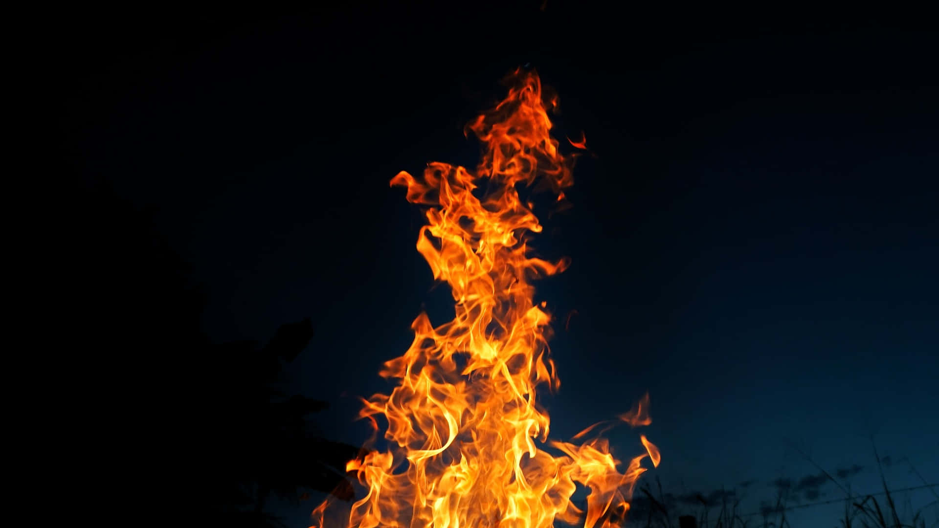 Burn 桌布 壁紙 — 鮮豔的橙色火焰在深沉的暮色天空中向上翻騰，底部有剪影般的草。