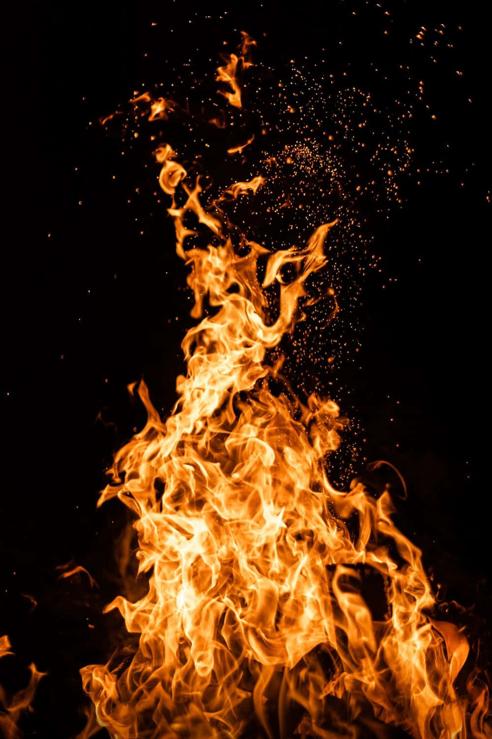 Flames 桌布 壁紙 — 鮮豔的橙色火焰在漆黑的背景上向上翻騰，上方飄浮著發光的餘燼。