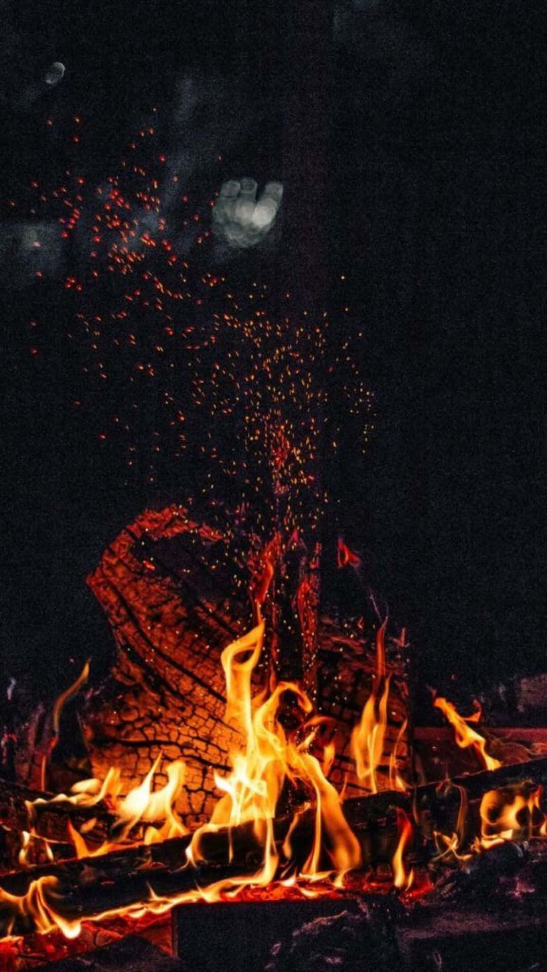 Flame 桌布 壁紙 — 鮮豔的橙色火焰從燃燒的木頭中躍出，熾熱的餘燼向上爆發，映襯著可見月亮的黑暗夜空。