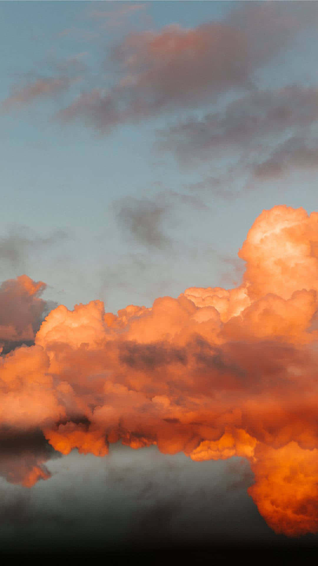 Clouds Aesthetic Tumblr 桌布 壁紙 — 鮮豔的橙色雲朵在下方平靜的水面倒映著的昏暗藍色天空中發光。