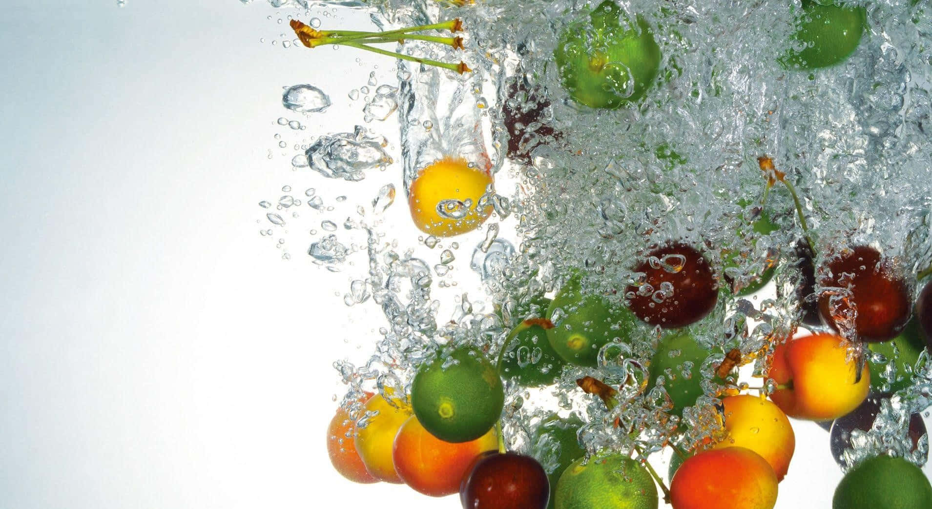 Fruits 桌布 壁紙 — 鮮豔的櫻桃和李子動態地飛濺穿過清澈的水，產生閃閃發光的氣泡和鮮明的色彩對比。