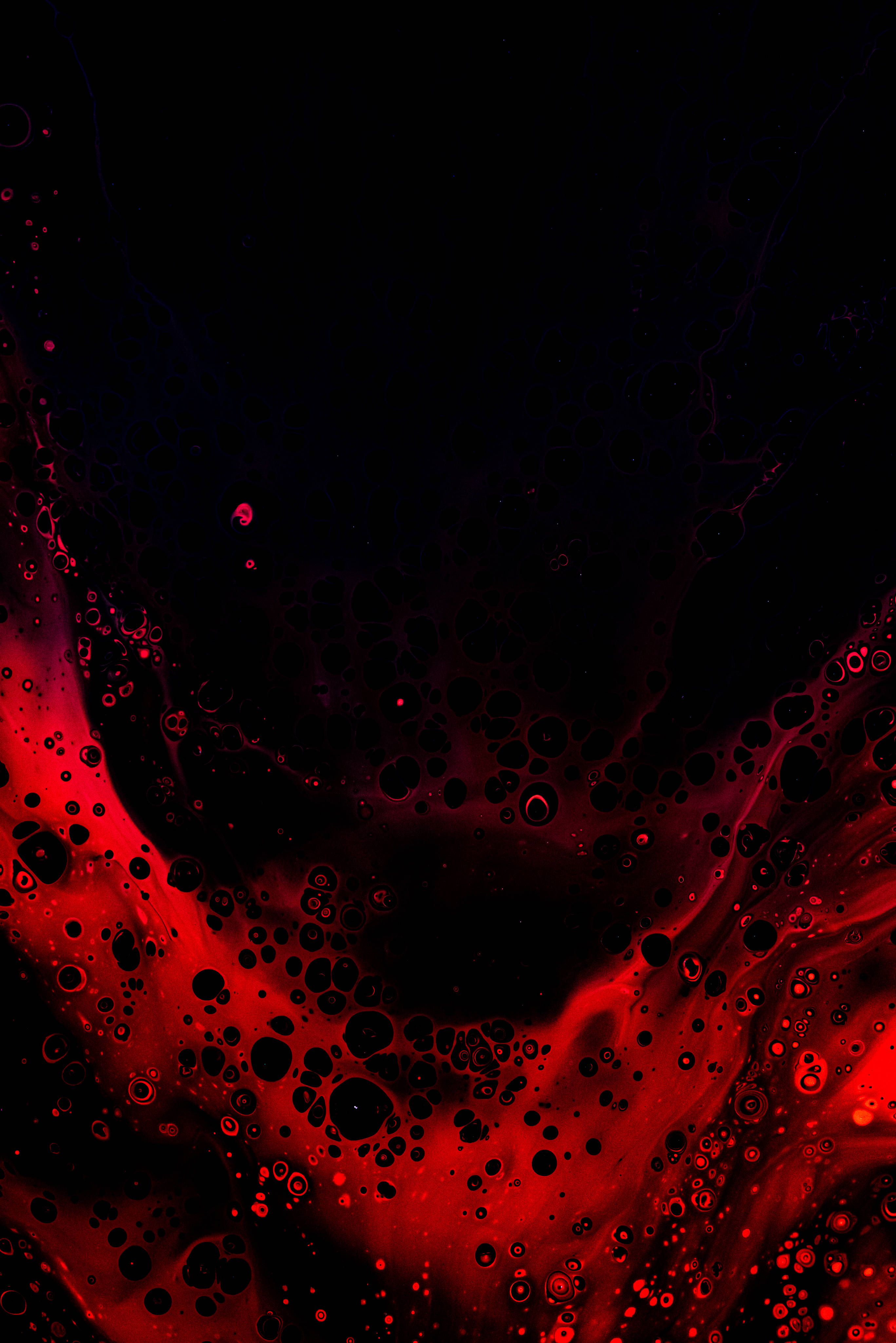 Red And Black iPhone 桌布 壁紙 — 鮮豔的深紅色液體在深黑色背景上流動，形成發光氣泡和旋轉觸手的抽象圖案。