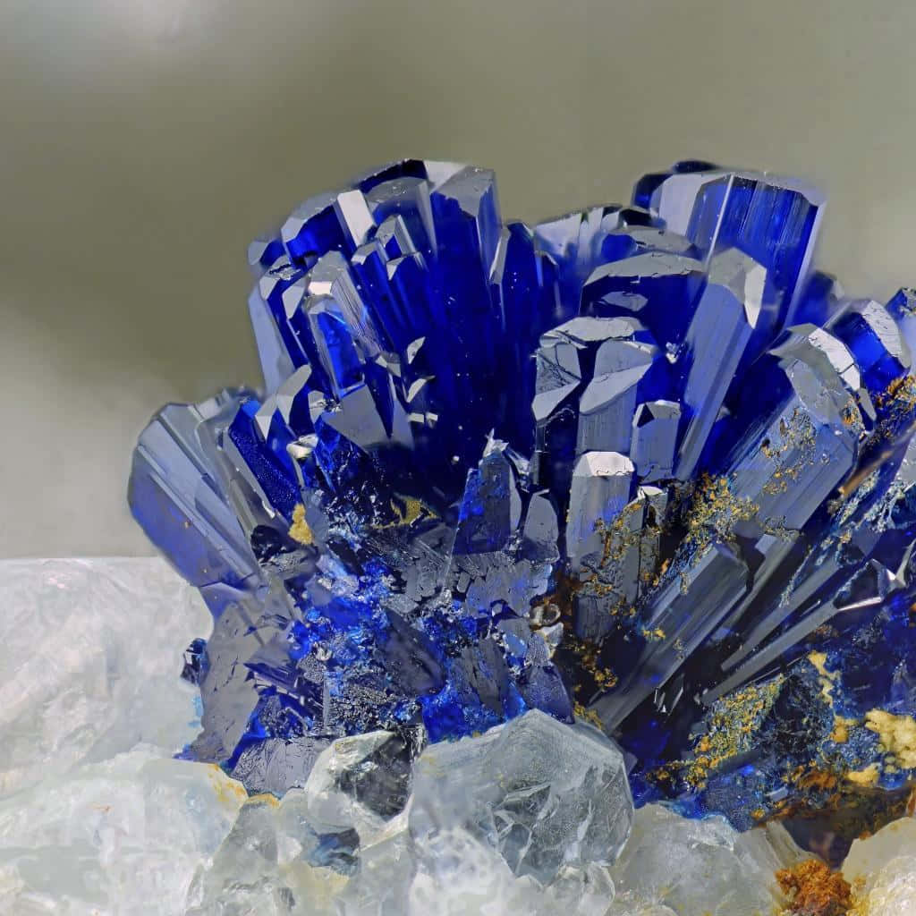 Gemstone 桌布 壁紙 — 鮮豔的深藍色晶體結構，帶有銳利的刻面和金色內含物，放置在透明石英上，背景為中性色調。