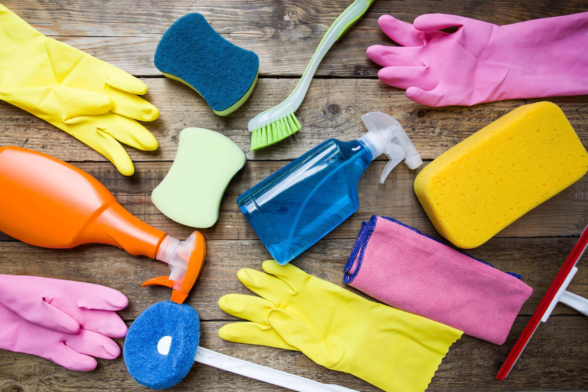 Cleaning 桌布 壁紙 — 鮮豔的清潔用品，包括手套、海綿和噴霧，排列在質樸的木質表面上。
