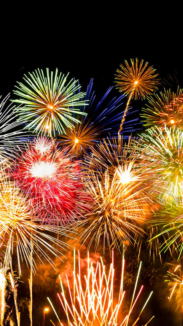 firework 桌布 壁紙 — 鮮豔的煙火在黑暗的夜空中綻放出耀眼的紅、綠、藍、金色光芒。