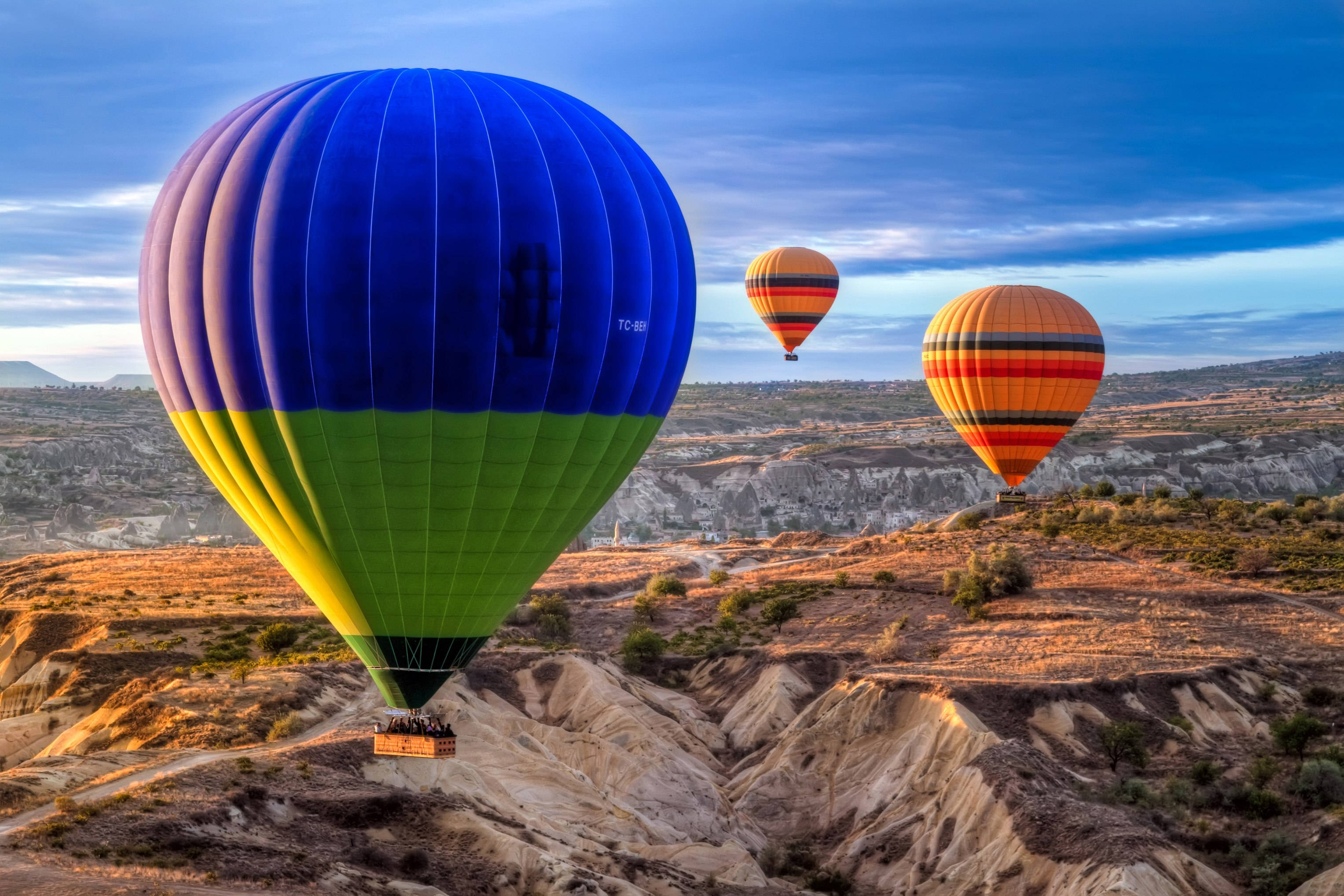 Cappadocia 桌布 壁紙 — 鮮豔的熱氣球在暮色天空下飄過崎嶇的卡帕多奇亞地形。