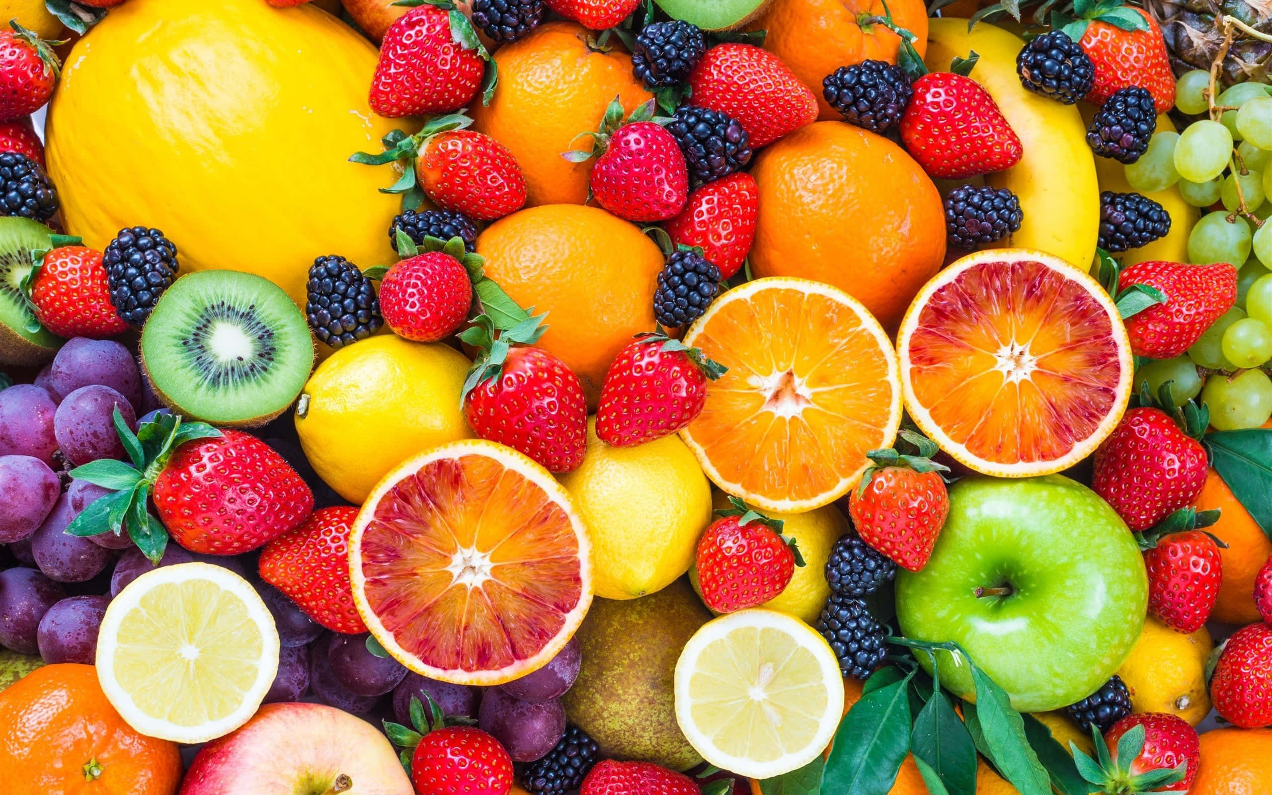 Fruit 桌布 壁紙 — 鮮豔的特寫鏡頭，展示各種新鮮水果，包括草莓、柳橙、奇異果和葡萄，以色彩繽紛且密集的方式排列。