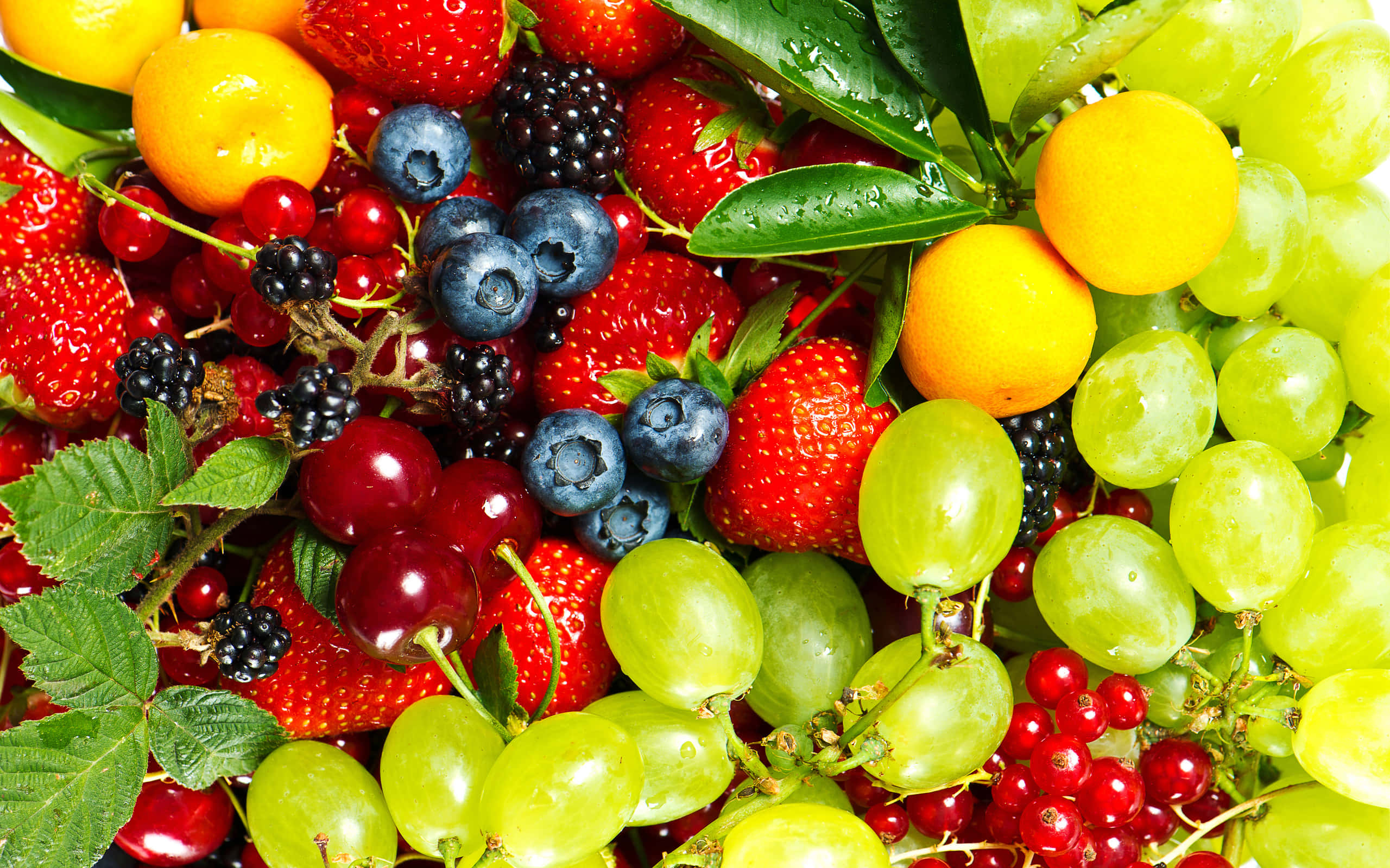 Fruit 桌布 壁紙 — 鮮豔的特寫鏡頭，展示各種新鮮漿果和葡萄，帶有露水的葉子在明亮光線下。