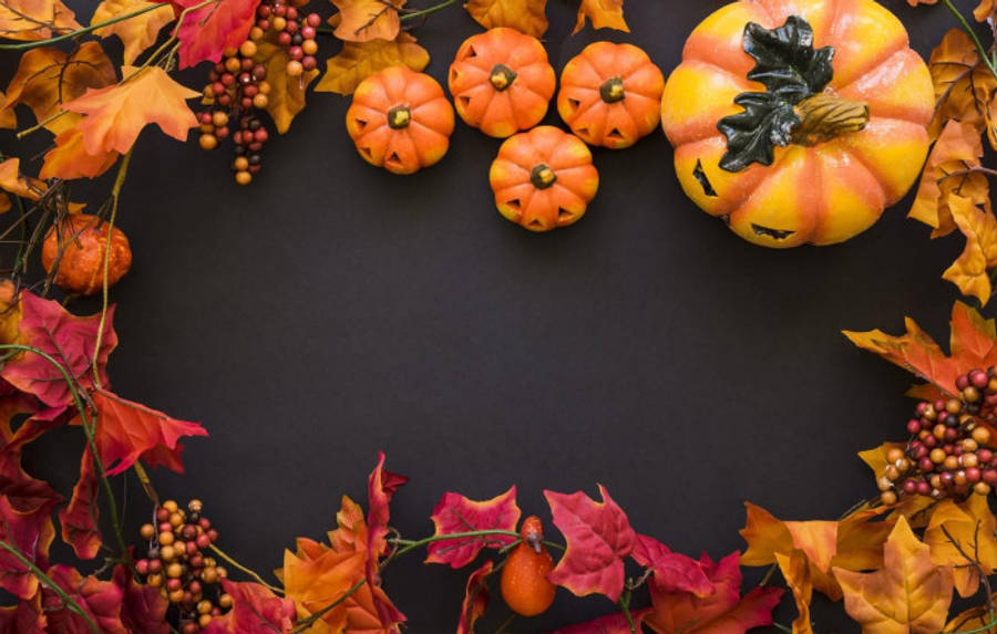 Fall 桌布 壁紙 — 鮮豔的秋葉和南瓜在深色背景上排列成節日邊框。