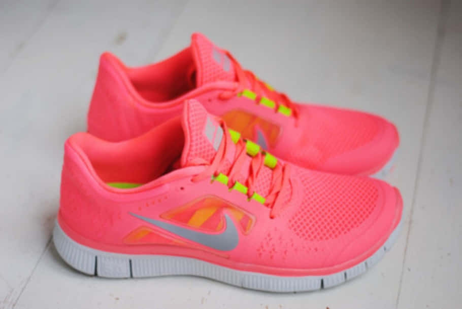 Pink Shoes 桌布 壁紙 — 鮮豔的粉紅色Nike跑鞋搭配螢光鞋帶，放置在淺色木地板上。