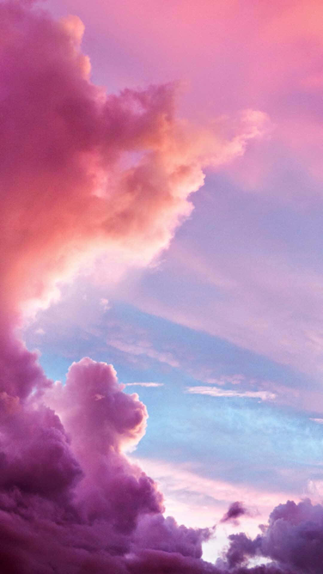 Pink Clouds 桌布 壁紙 — 鮮豔的粉紅色和紫色雲彩在暮色中戲劇性地在柔和的藍色天空中旋轉。