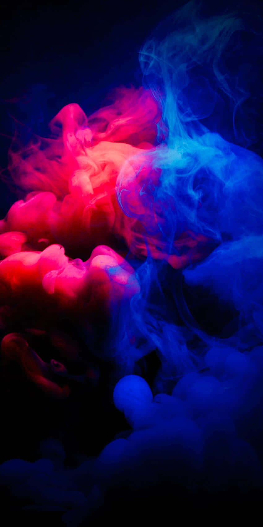Red Smoke Effect 桌布 壁紙 — 鮮豔的粉紅色和藍色煙霧在深黑色背景上戲劇性地旋轉，形成動態的抽象構圖。