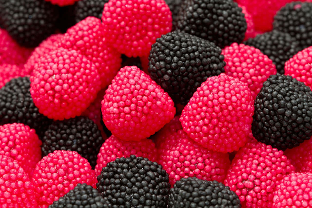 Raspberry 桌布 壁紙 — 鮮豔的粉紅色和黑色覆盆子緊密堆疊，在明亮光線下展示其紋理表面。