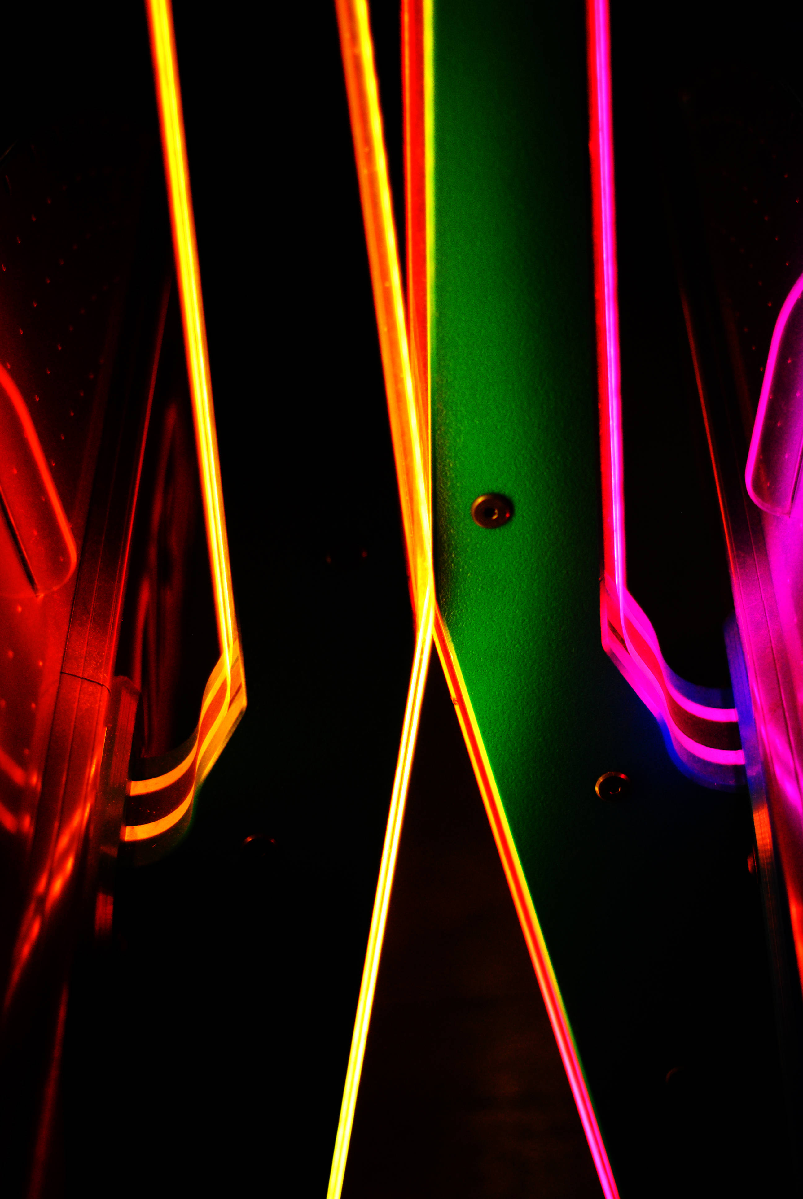Neon Phone 桌布 壁紙 — 鮮豔的紅、橙、綠和粉紅色霓虹燈光在黑色背景上對角線延伸，營造出動態的抽象光芒。