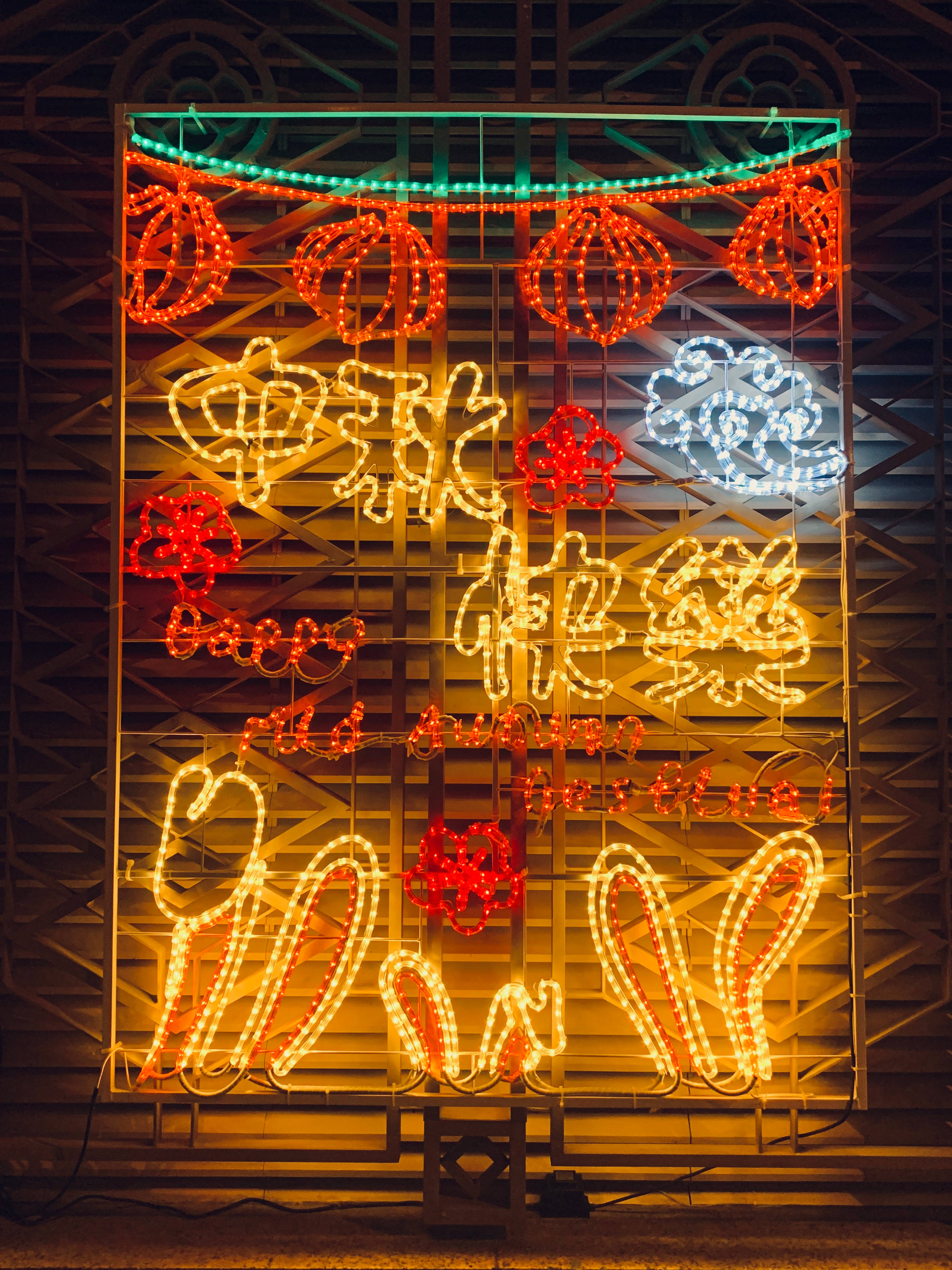 Neon Phone 桌布 壁紙 — 鮮豔的紅、黃、藍色霓虹燈在夜間形成喜慶的中文字和燈籠，映襯著深色金屬門。
