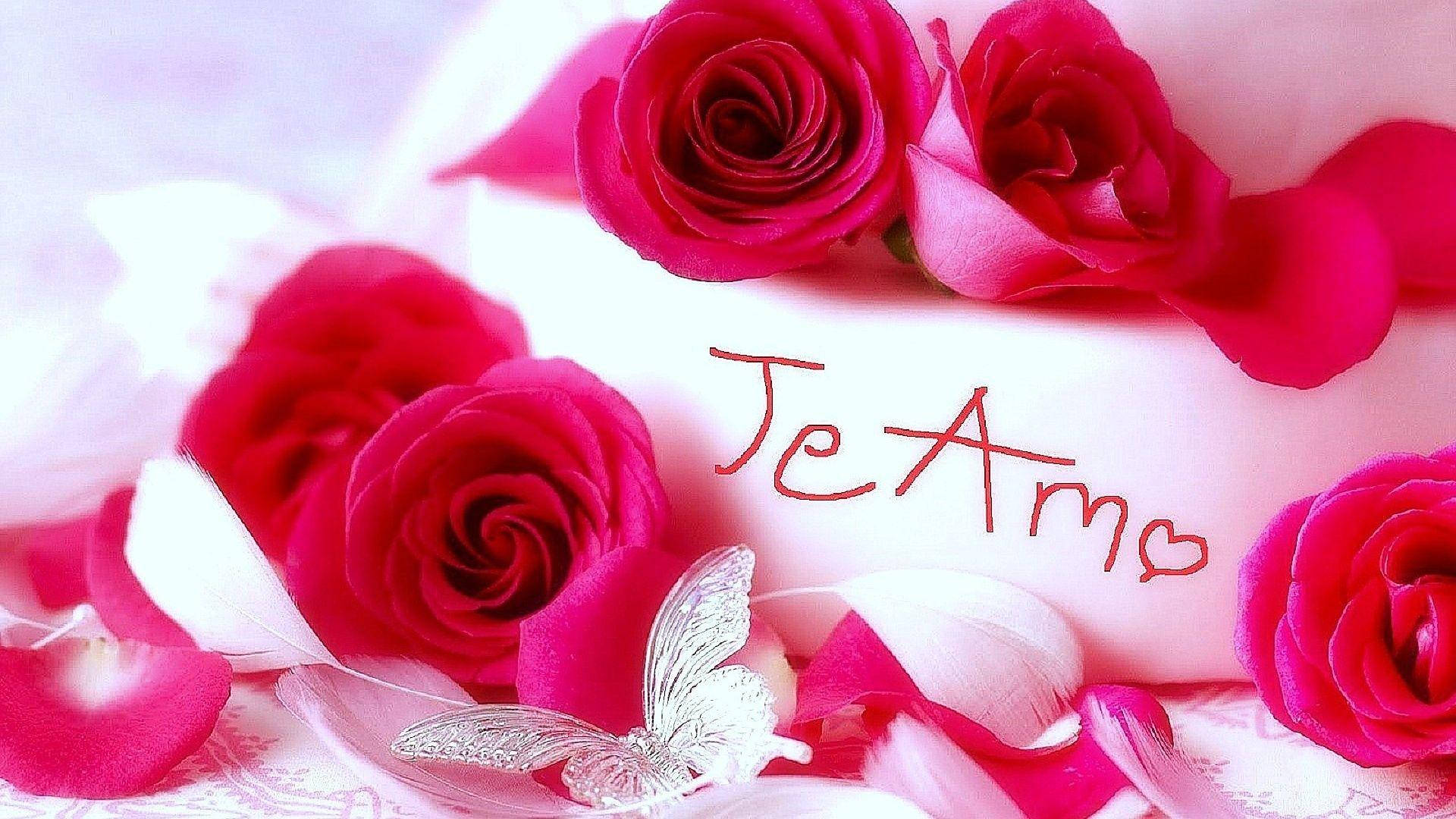 Te Amo 桌布 壁紙 — 鮮豔的紅玫瑰和散落的花瓣圍繞著一個帶有 'Je T'aime' 字樣和銀色蝴蝶的白色心形。