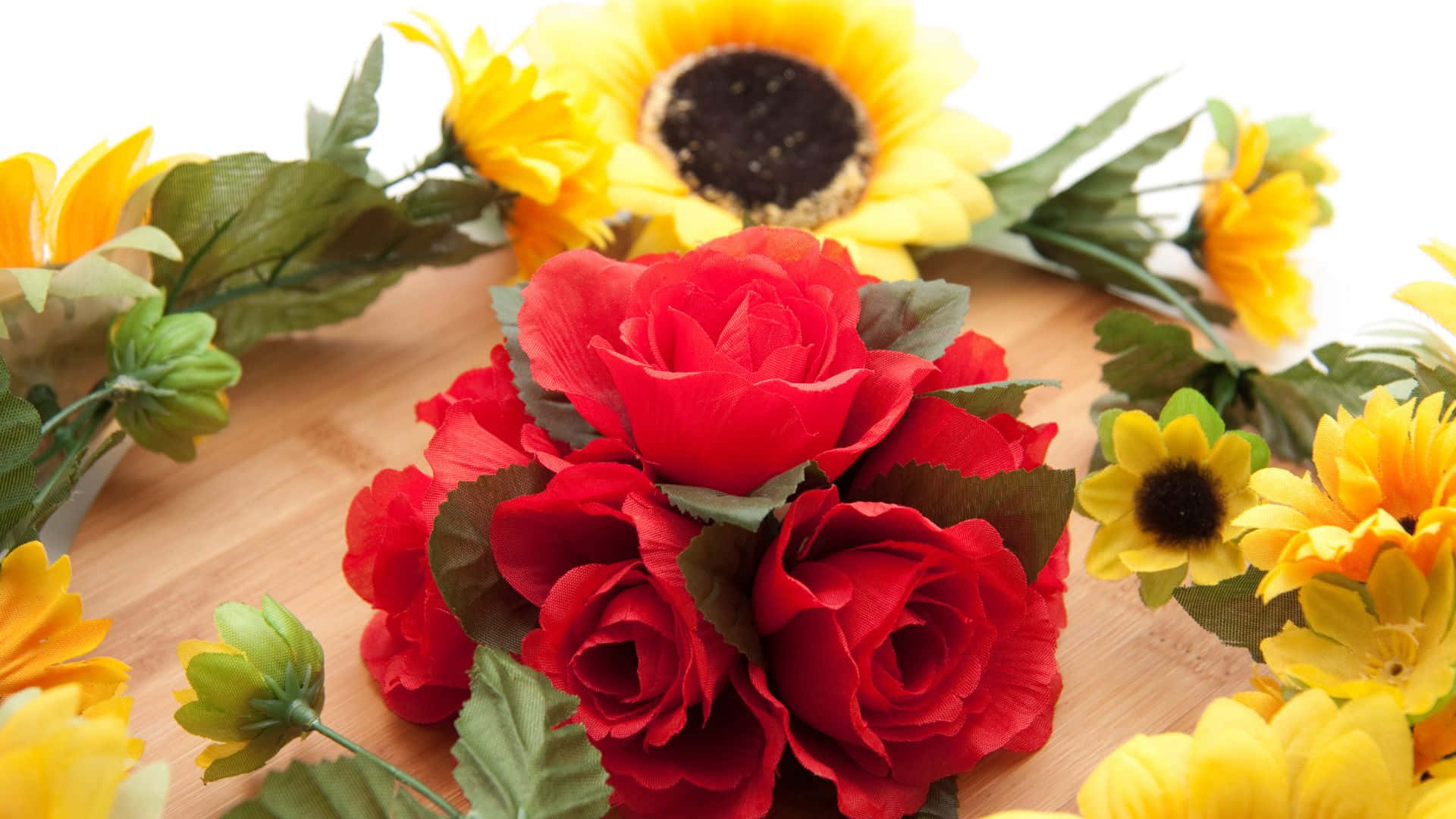 Roses 桌布 壁紙 — 鮮豔的紅玫瑰和黃色向日葵排列在淺色木質表面上，搭配綠色葉子。