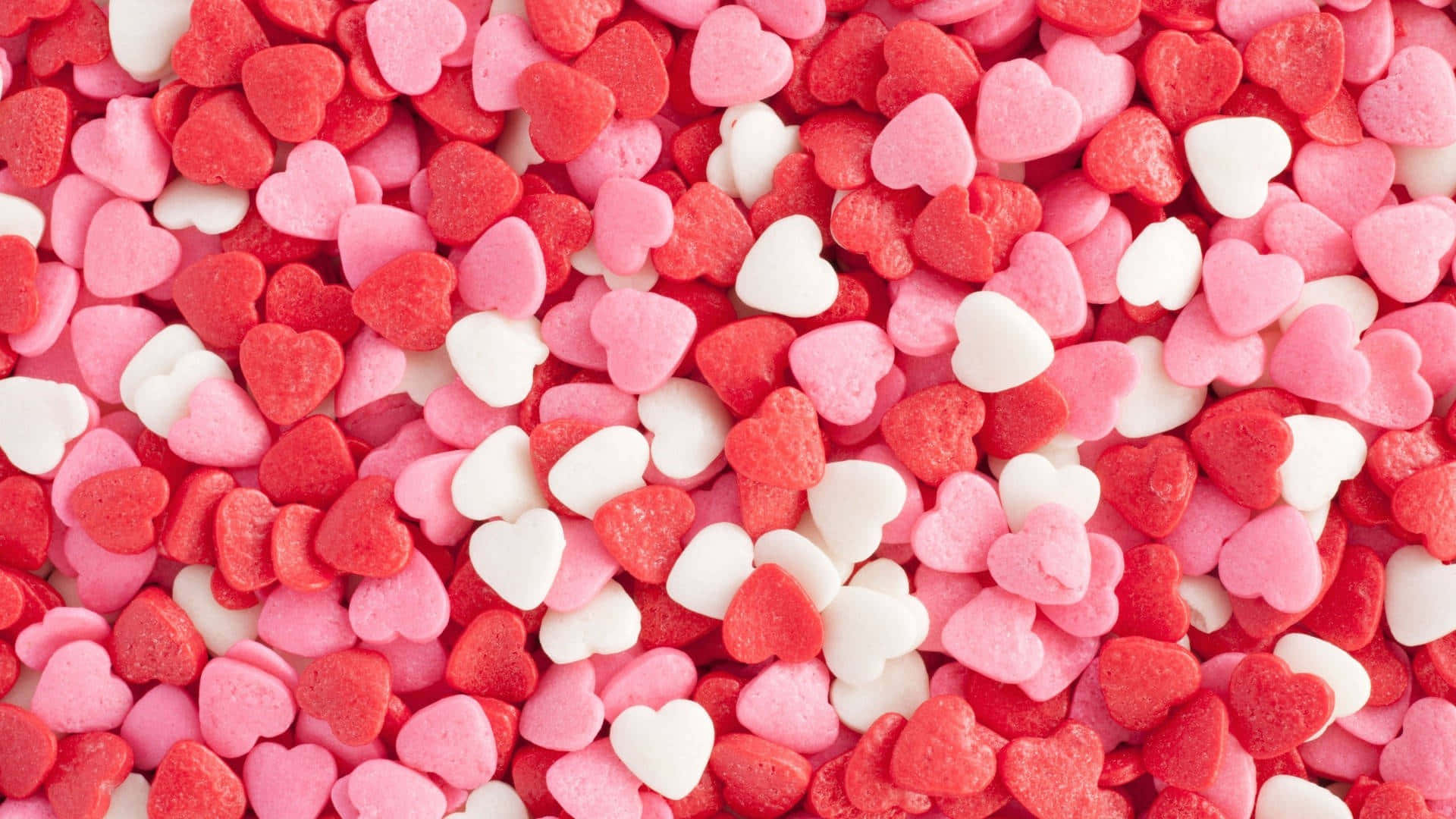 Candy Aesthetic 桌布 壁紙 — 鮮豔的紅色、粉紅色和白色心形糖果灑在畫面中密集散落的特寫。