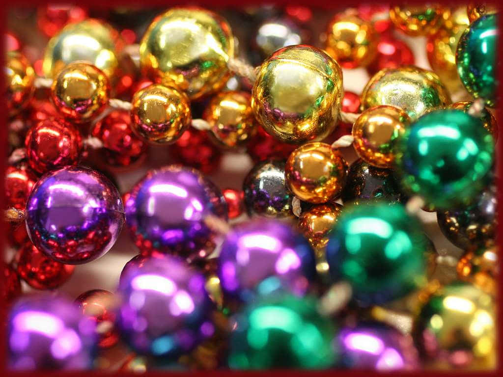 Mardi Gras 桌布 壁紙 — 鮮豔的紅色、紫色、綠色和金色閃亮金屬珠子串在一起的近距離特寫。
