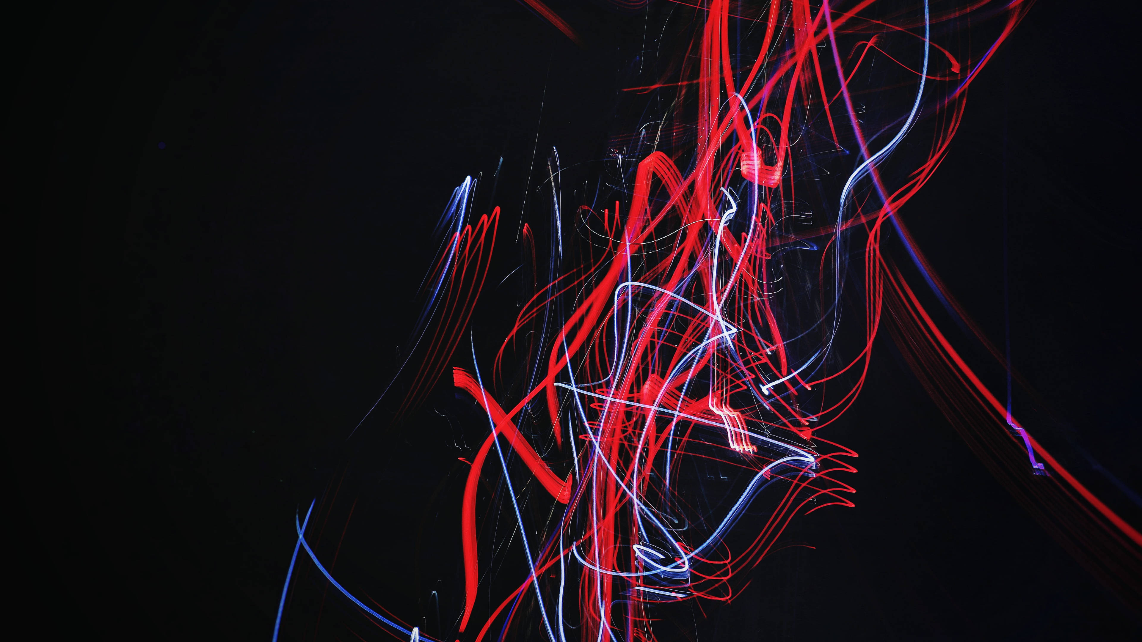 lights 桌布 壁紙 — 鮮豔的紅色、藍色和白色光軌在深黑色背景上動態旋轉，這是一張長曝光照片。