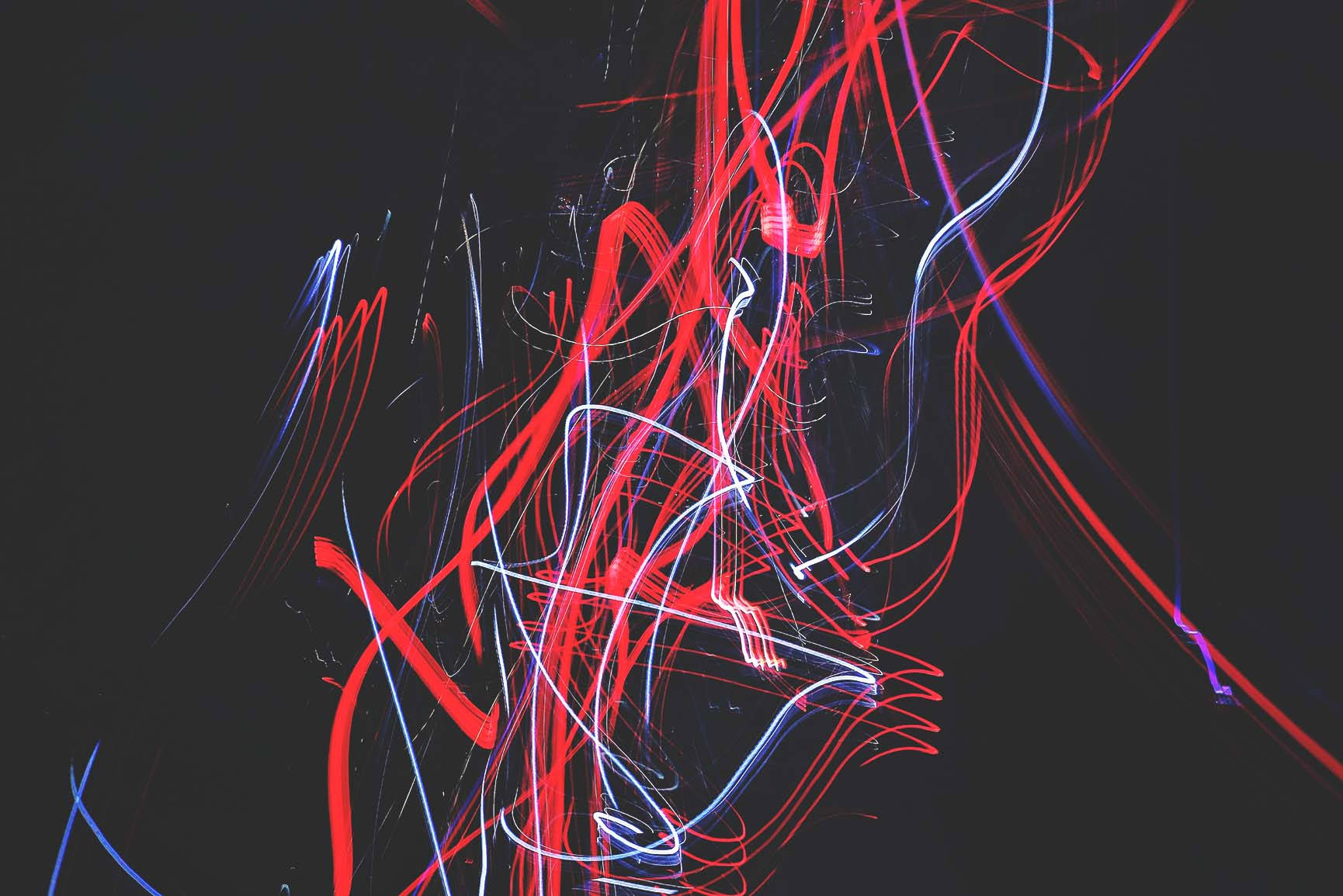 Red And Black iPhone 桌布 壁紙 — 鮮豔的紅色、藍色和白色光軌在黑暗背景上劃過，形成動態抽象構圖。