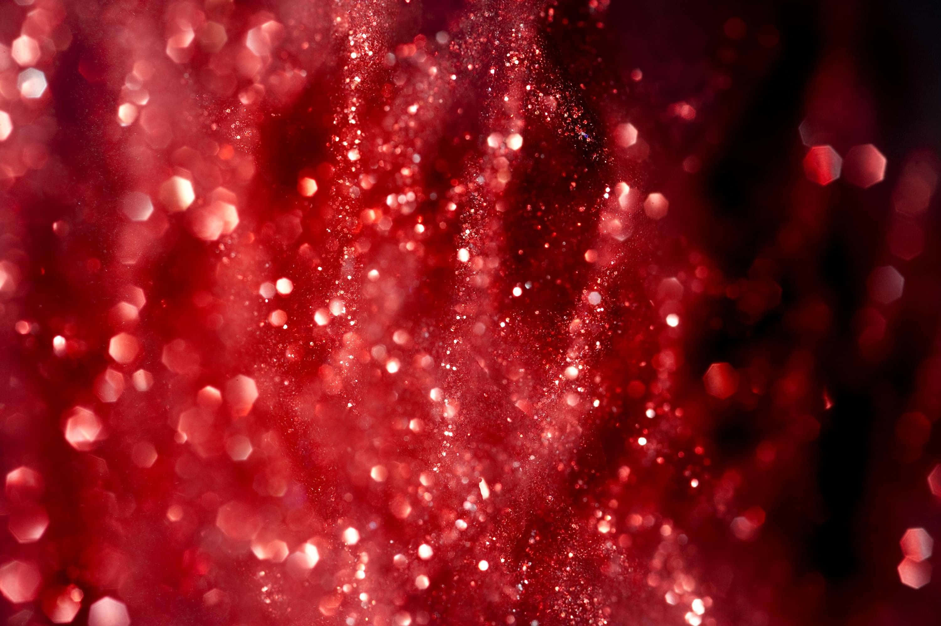 Red Cute Aesthetic 桌布 壁紙 — 鮮豔的紅色亮粉顆粒在柔和的散景光中旋轉，背景為深色。
